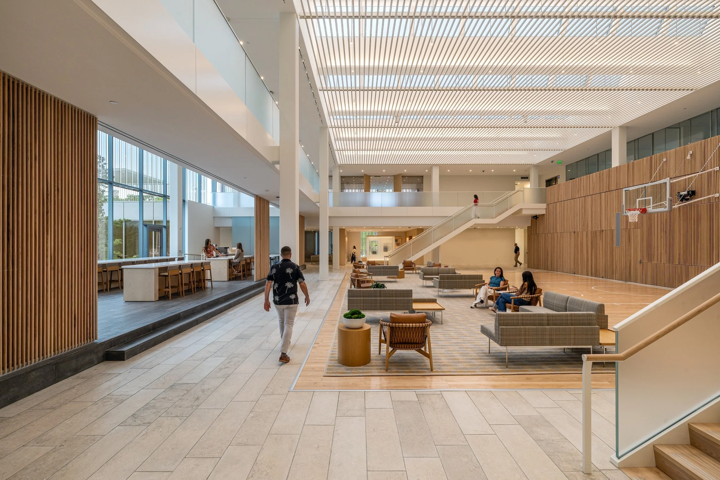 open flexible use gathering space with ambient light, sliding wood panel doors, and a basketball court