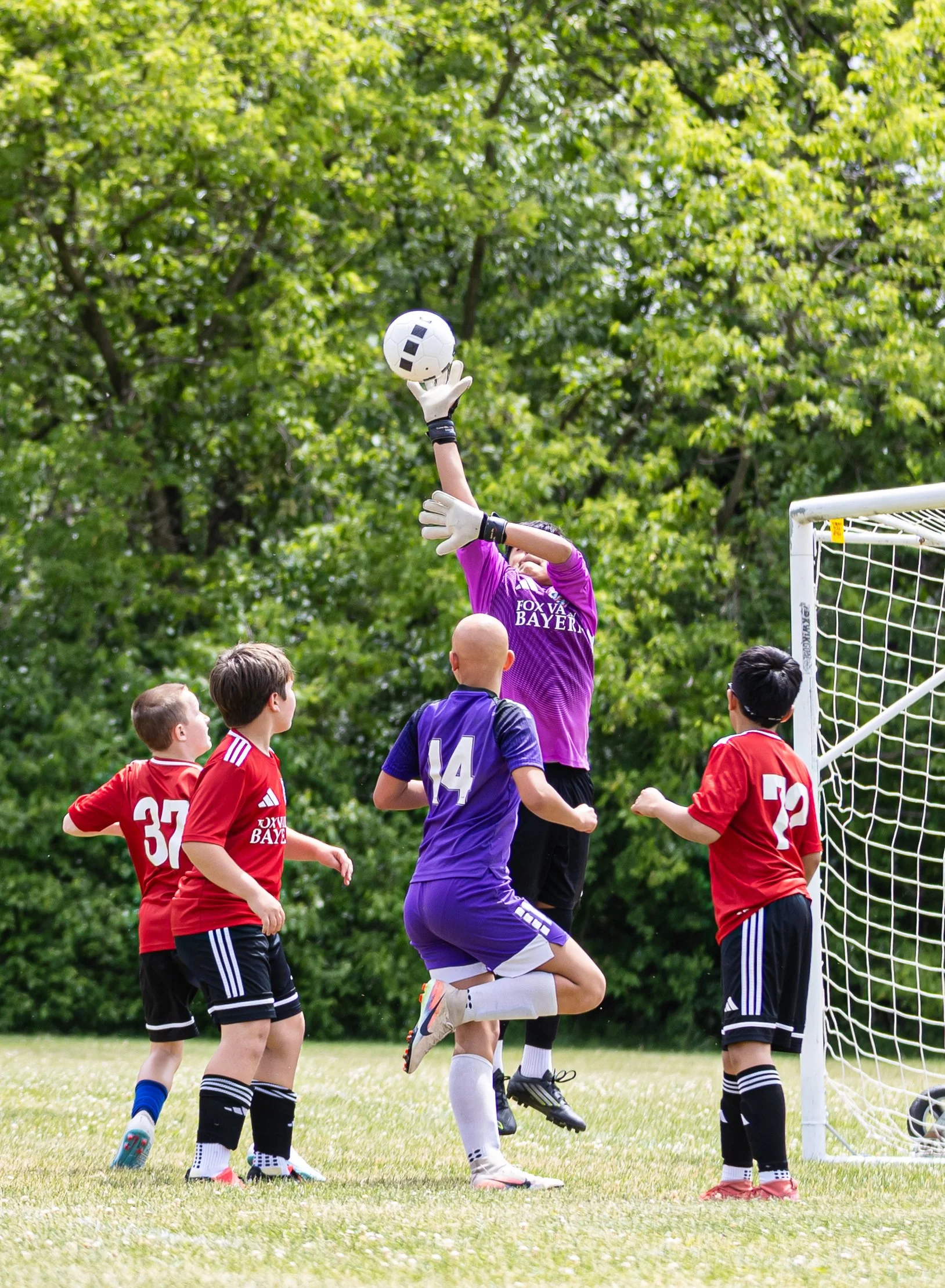 Youth soccer goalkeeper in action saving a goal. Action photography by Ania’s Little World Photography in the Chicago suburbs.