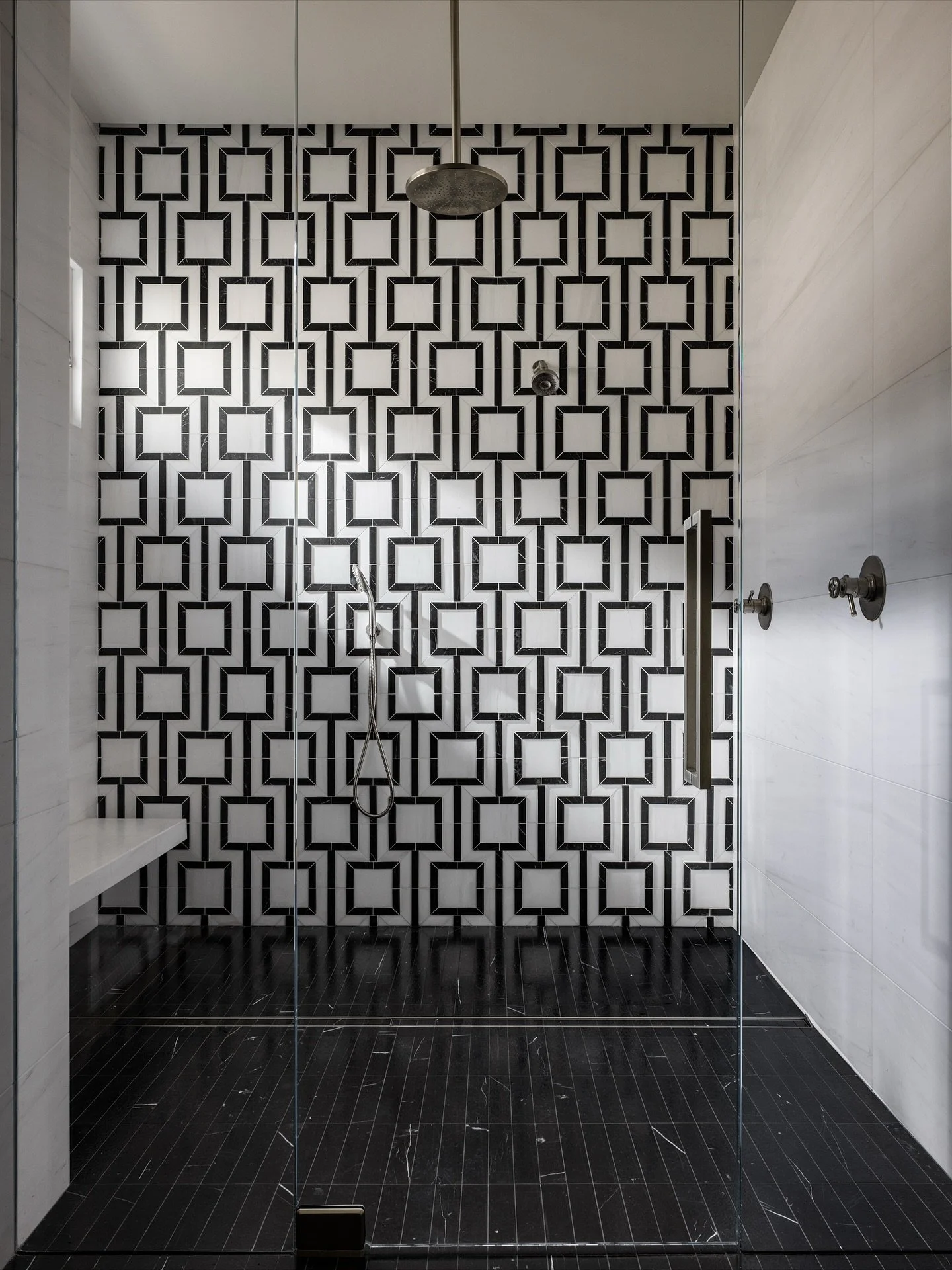 Pattern play meets modern minimalism.
The shower features the Meander dimensional waterjet mosaic by @maisonsurface, framed by Dolomite marble walls &mdash; a bold black-and-white statement balanced by soft oak cabinetry and natural light.

Builder: 
