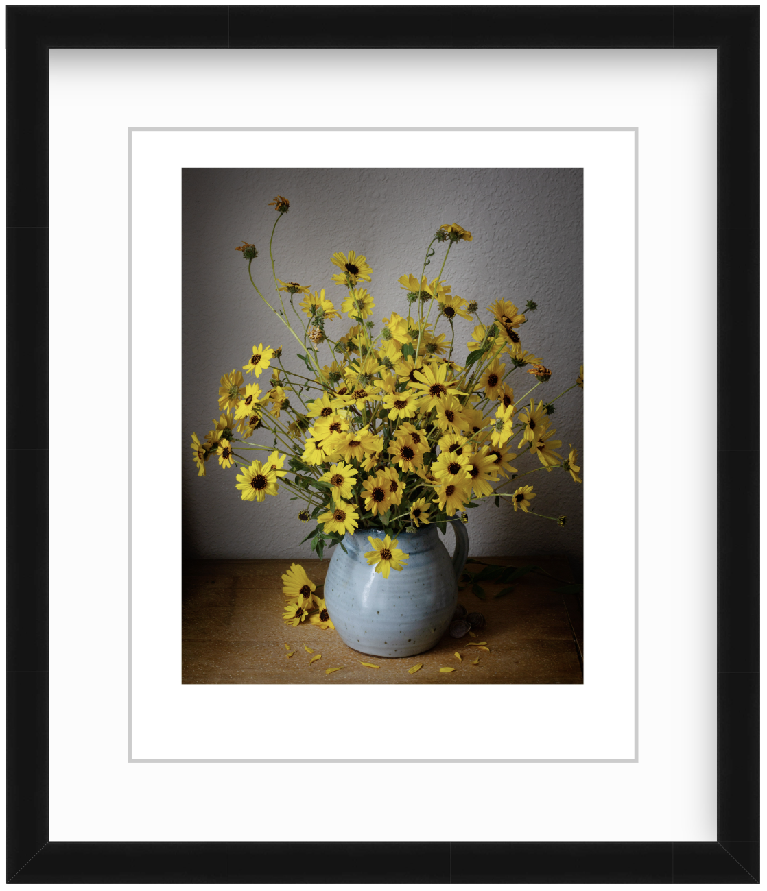 Wild sunflowers arranged in a moody still life composition with soft, dramatic lighting and dark background, emphasizing their natural, delicate form.