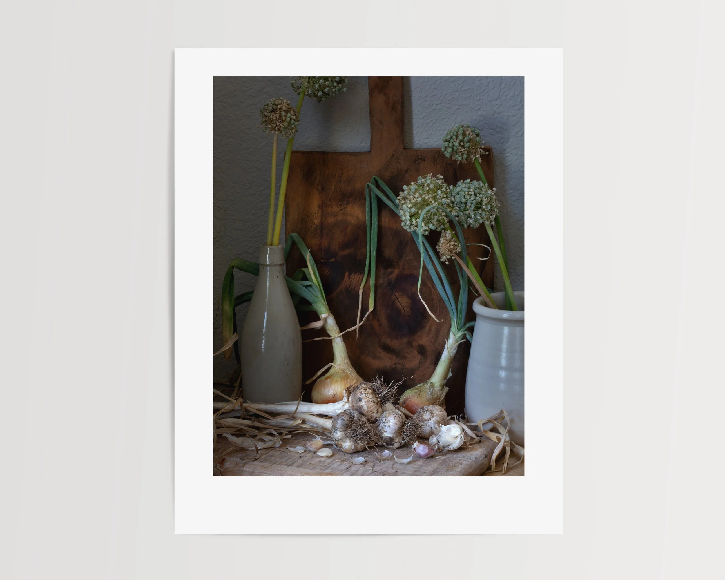 Moody still life photograph of onions and garlic arranged in soft, painterly lighting