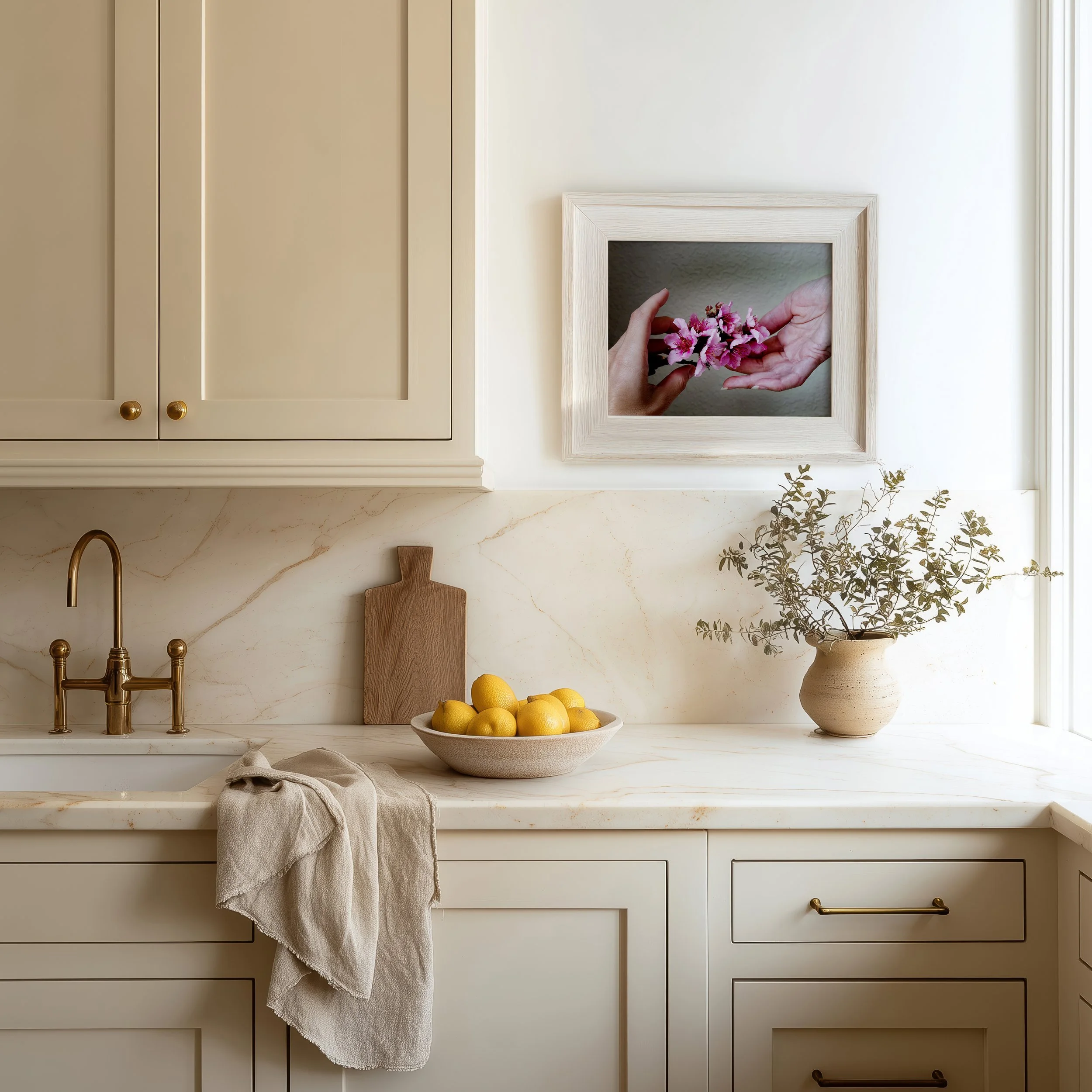 Two hands gently passing delicate peach blossoms framed in a kitchen