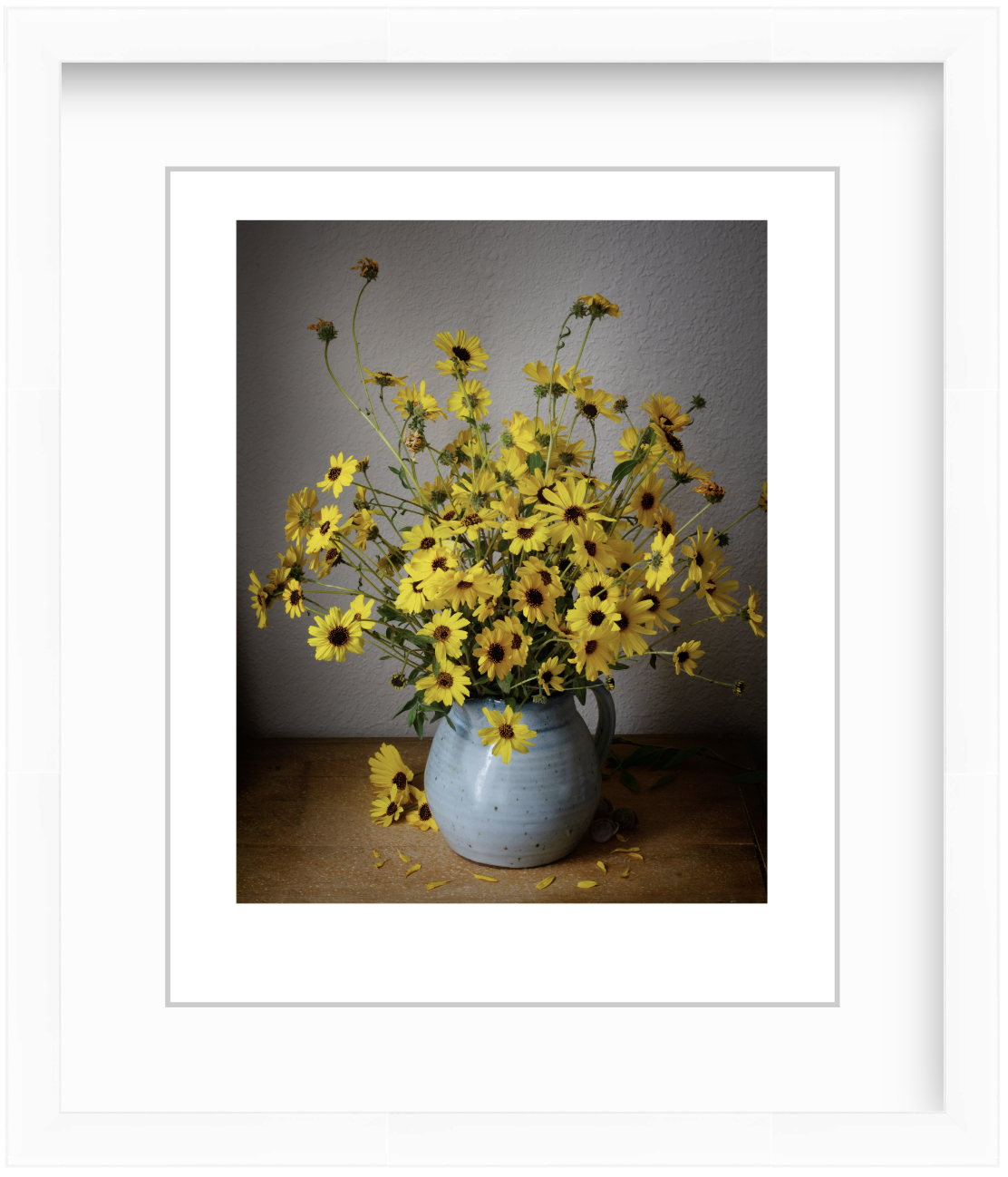 Wild sunflowers arranged in a moody still life composition with soft, dramatic lighting and dark background, emphasizing their natural, delicate form.