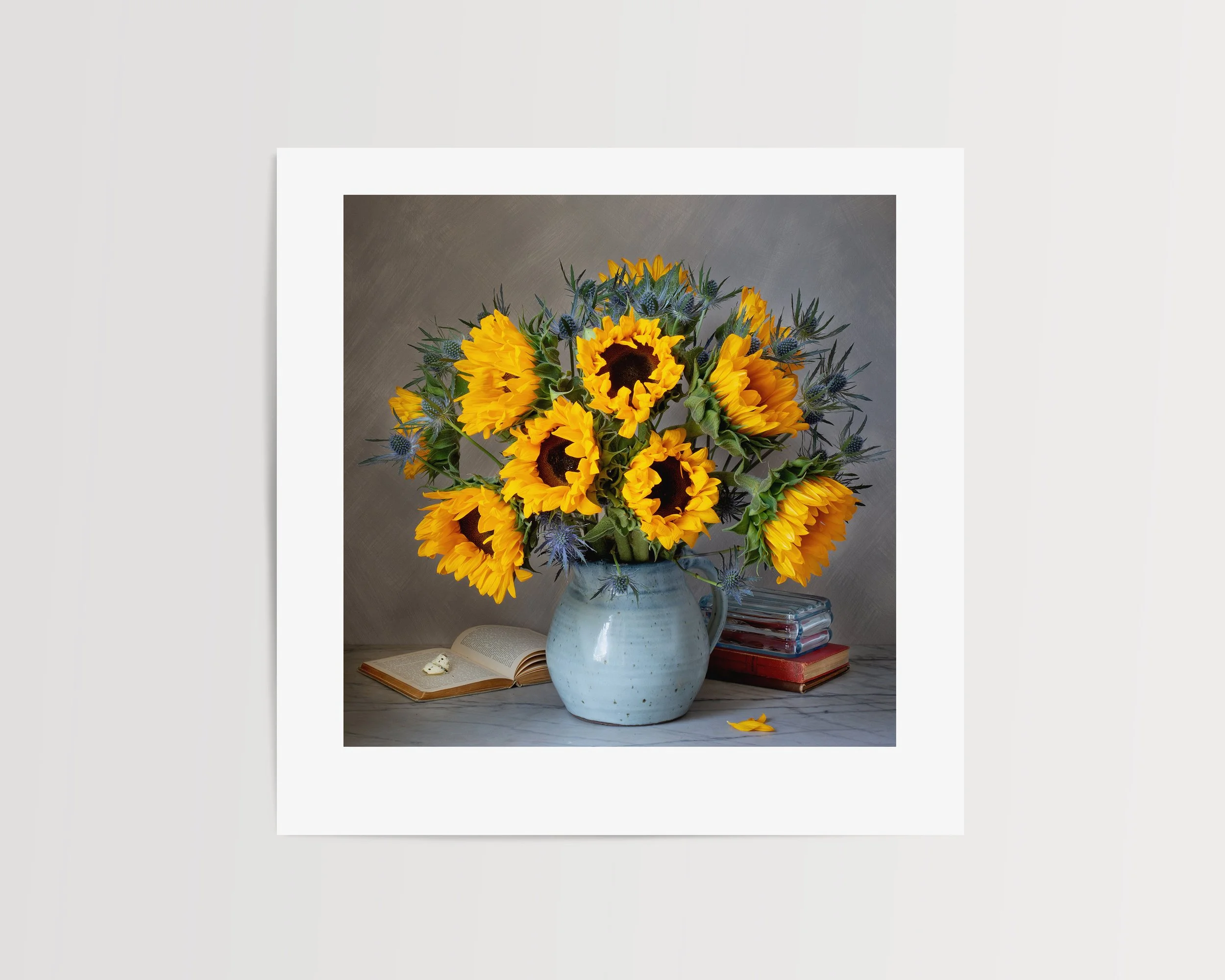 Sunflowers arranged with vintage books and a butterfly in a moody studio still life, lit with soft, dramatic lighting against a dark background.