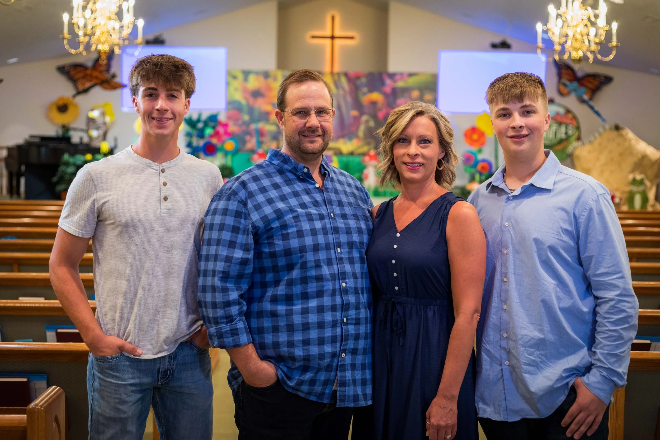 Smiling couple taking a selfie by a river with lush greenery in the background.