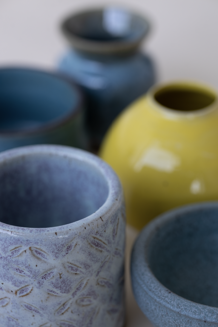 Set of colorful ceramic vases in blue, yellow, green, and gray colors with textured and smooth surfaces.