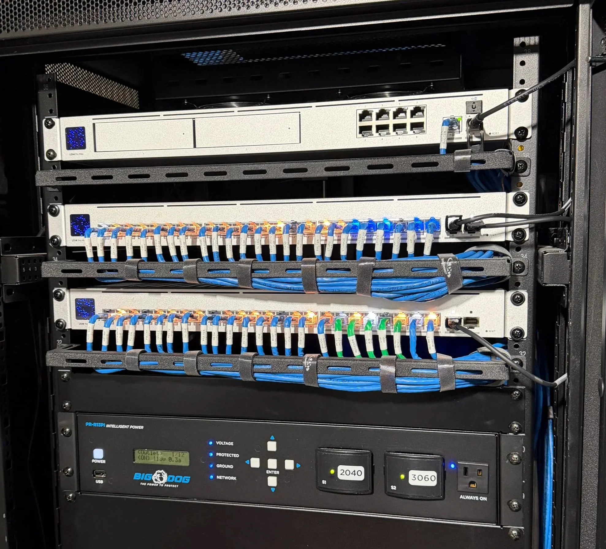 An advanced server rack with network switches, patch panels, and power supply units with blue cables connected to the switches. Includes products from Ubiquiti