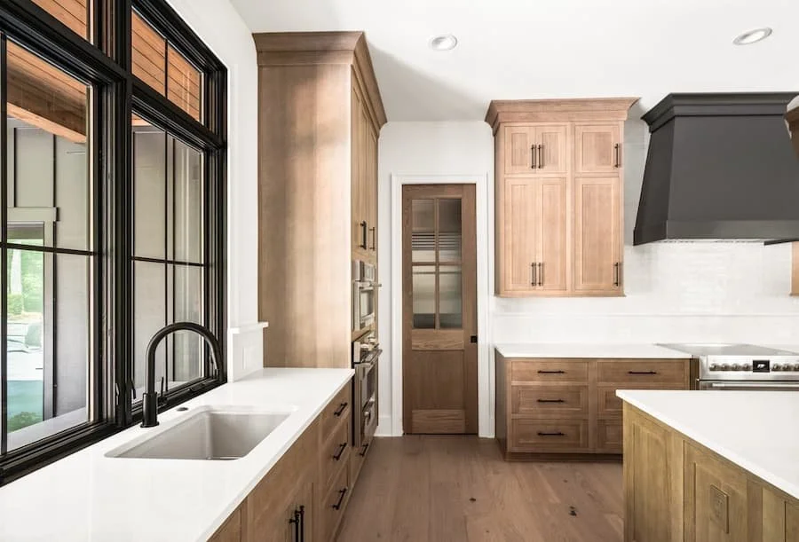 chefs kitchen - photo of a kitchen facing the pantry door with the sink and a large window on the left