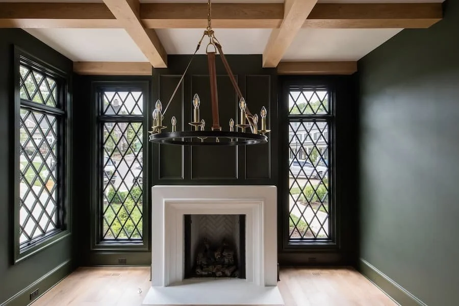 fireplace mantels / fireplace mantel ideas - clean white fireplace in a dark green room with expose beams on the ceiling