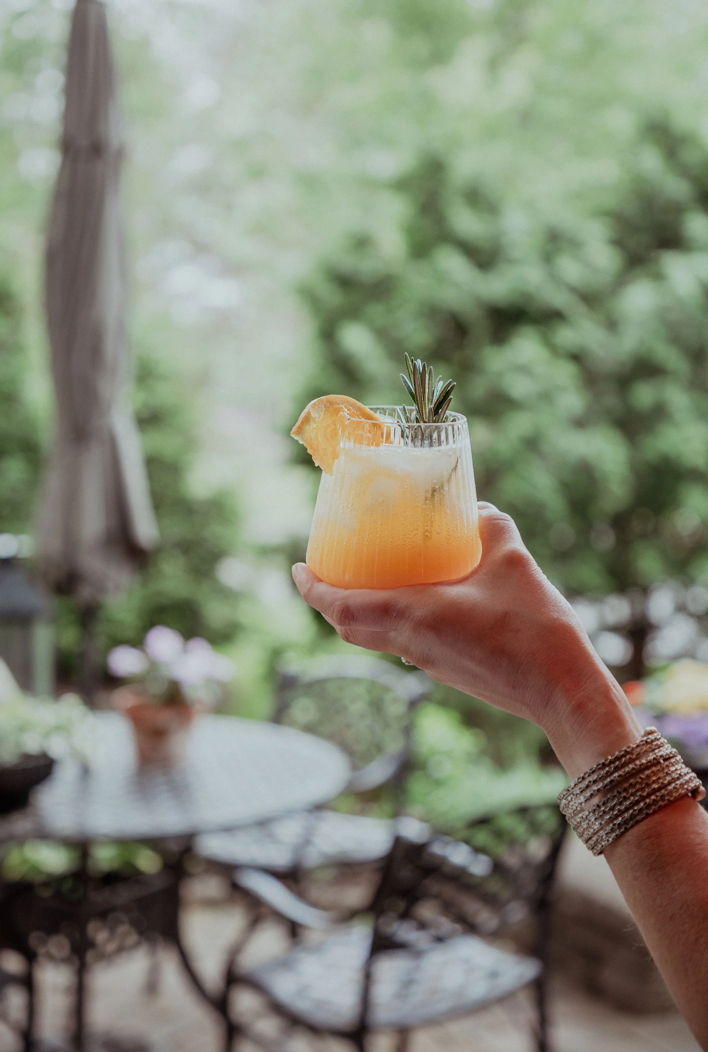 A citrus and rosemary mocktail held outdoors during a Mindful Mixer wellness experience.