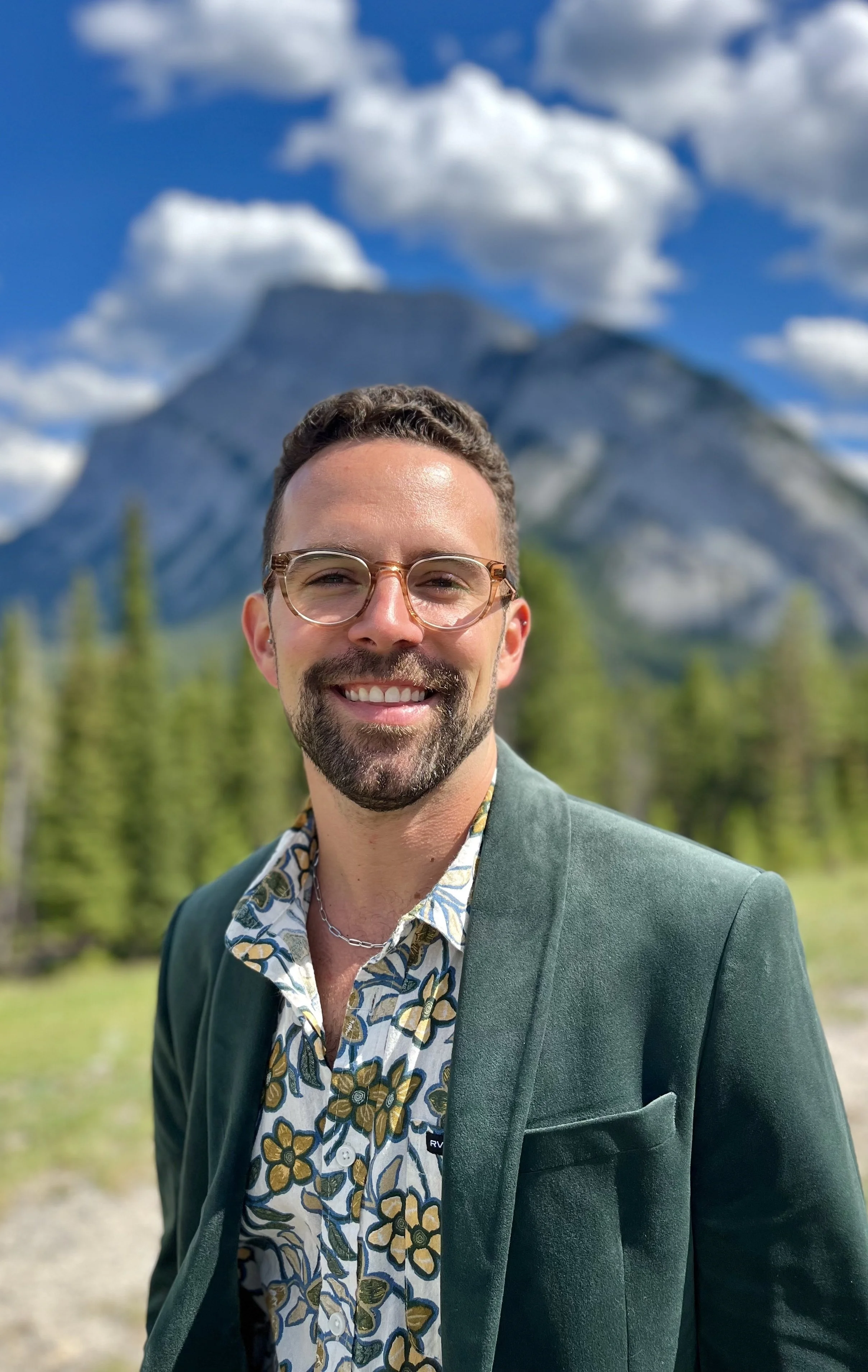 Person smiling outdoors with mountain backdrop