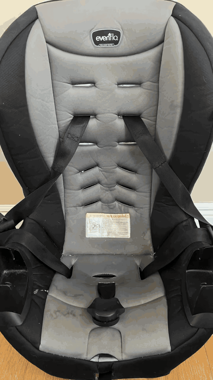 Gray and black Evenflo car seat with straps and warning label.