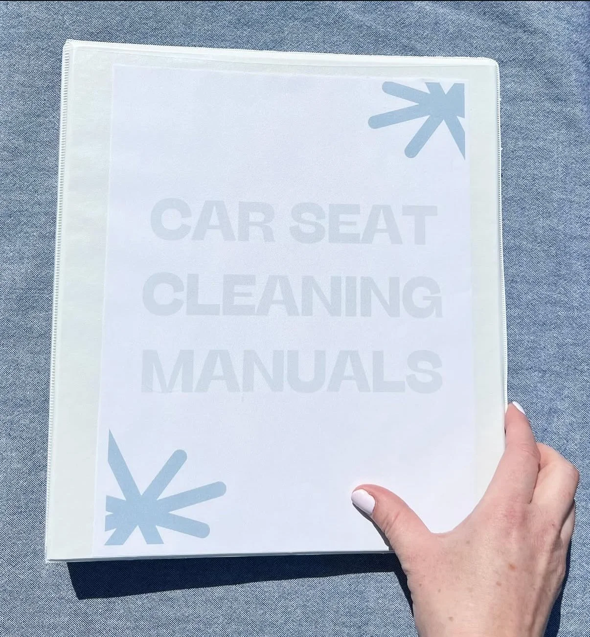 Binder labeled "Car Seat Cleaning Manuals" with a hand holding it.