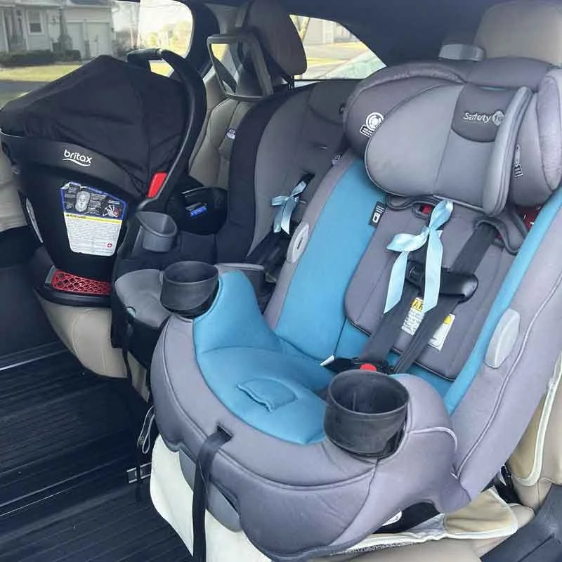 Car interior with two child safety seats, one is a Britax infant car seat and the other is a Safety 1st convertible car seat in blue and gray.