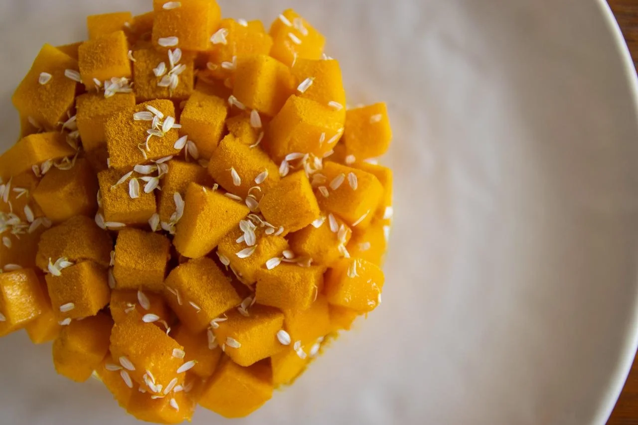A bowl of cubed mango topped with white sesame seeds.