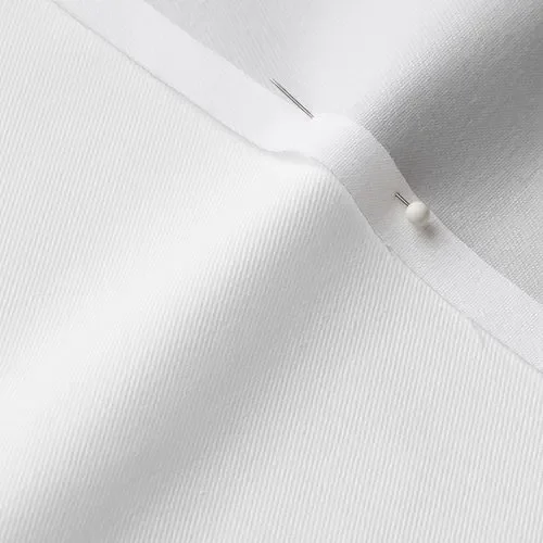 Close-up of white fabric with a pin and a pinhead holding the fabric in place.