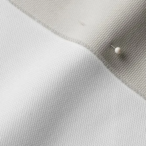 Close-up of white and beige textured fabric with a pin and a small needle