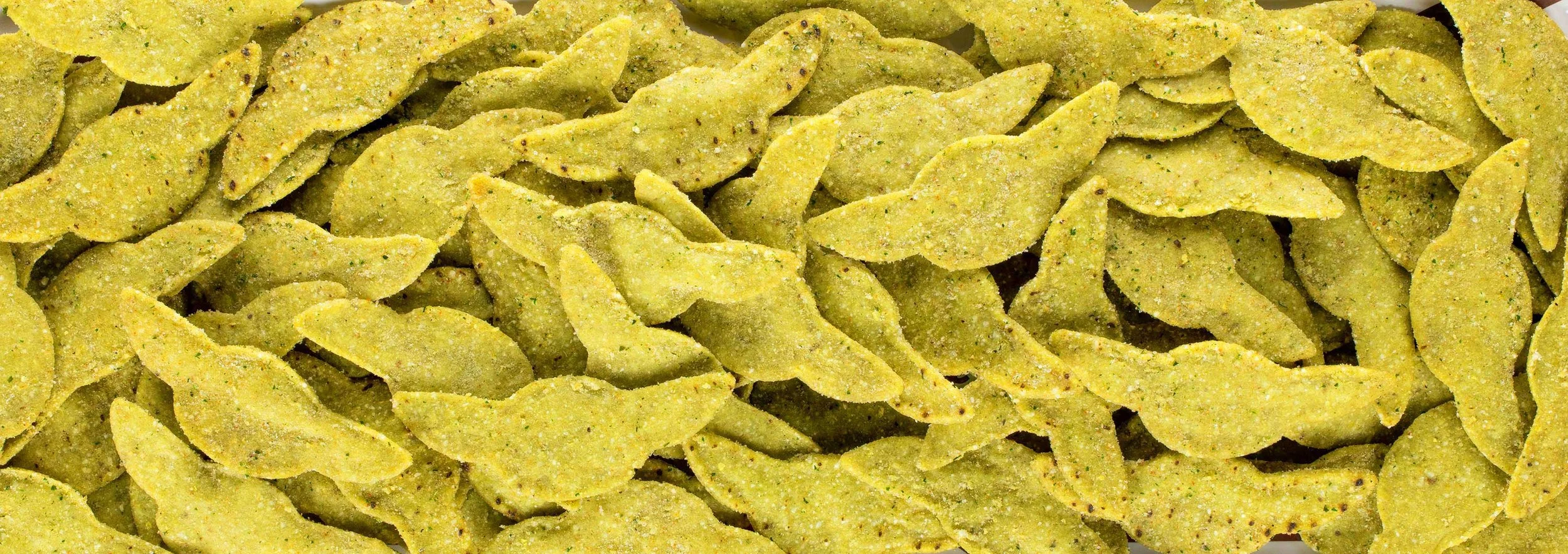 Close-up of green-colored, seasoned, crispy tortilla chips.