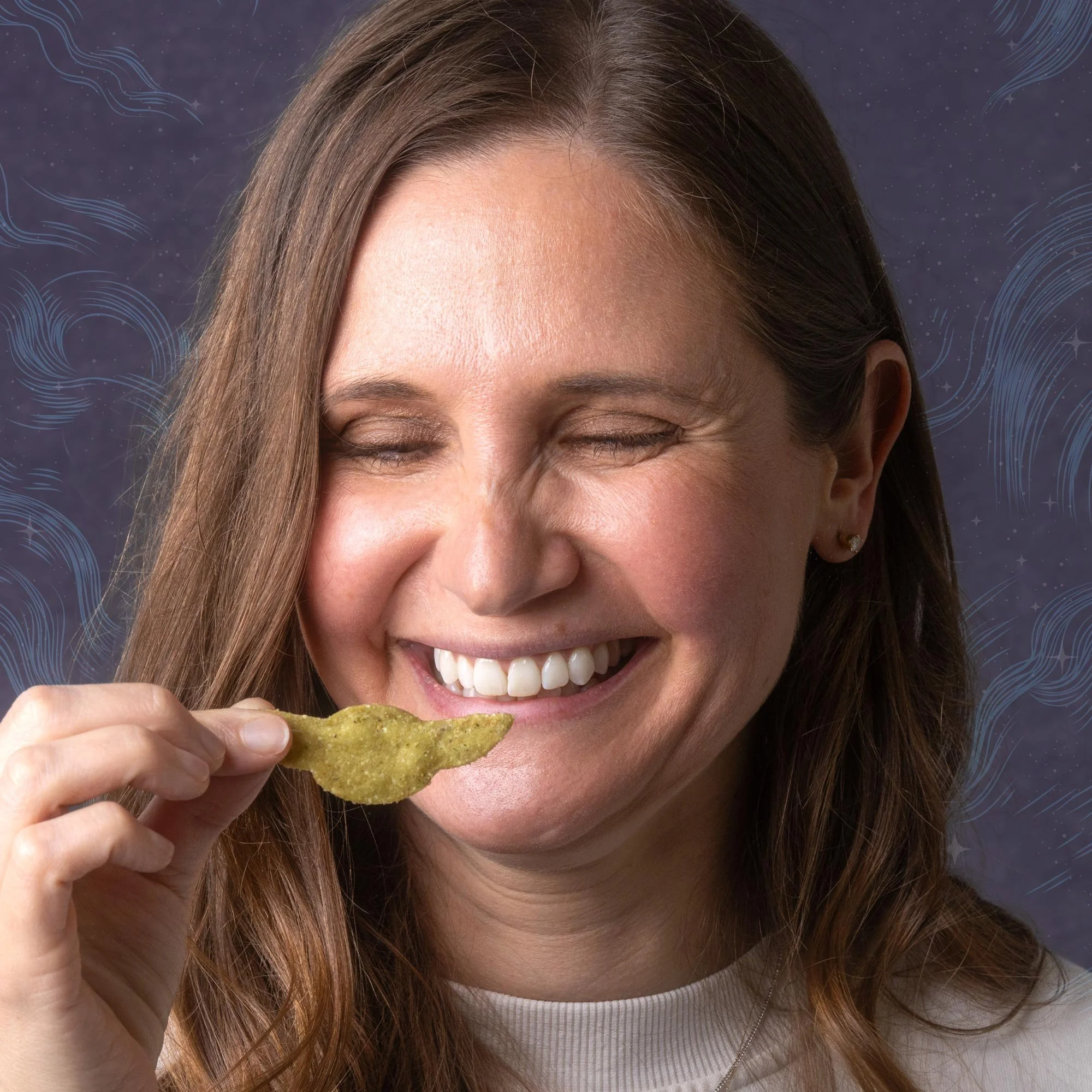 A woman with long brown hair smiling while holding a tortilla chip, set against a dark background with blue wavy patterns and small star-like dots.