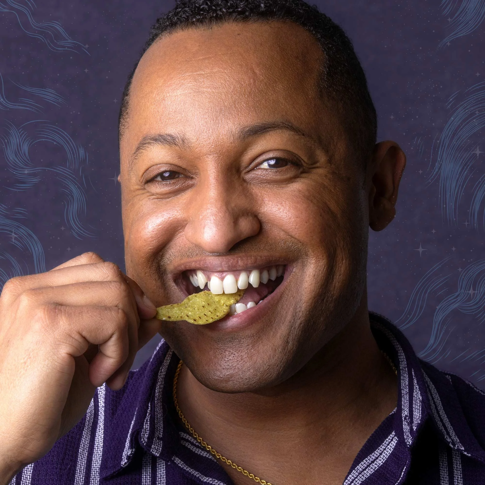 Close-up of a smiling man with short curly hair, holding a tortilla chip near his mouth, wearing a purple striped shirt and a gold chain, dark background with blue swirling patterns.