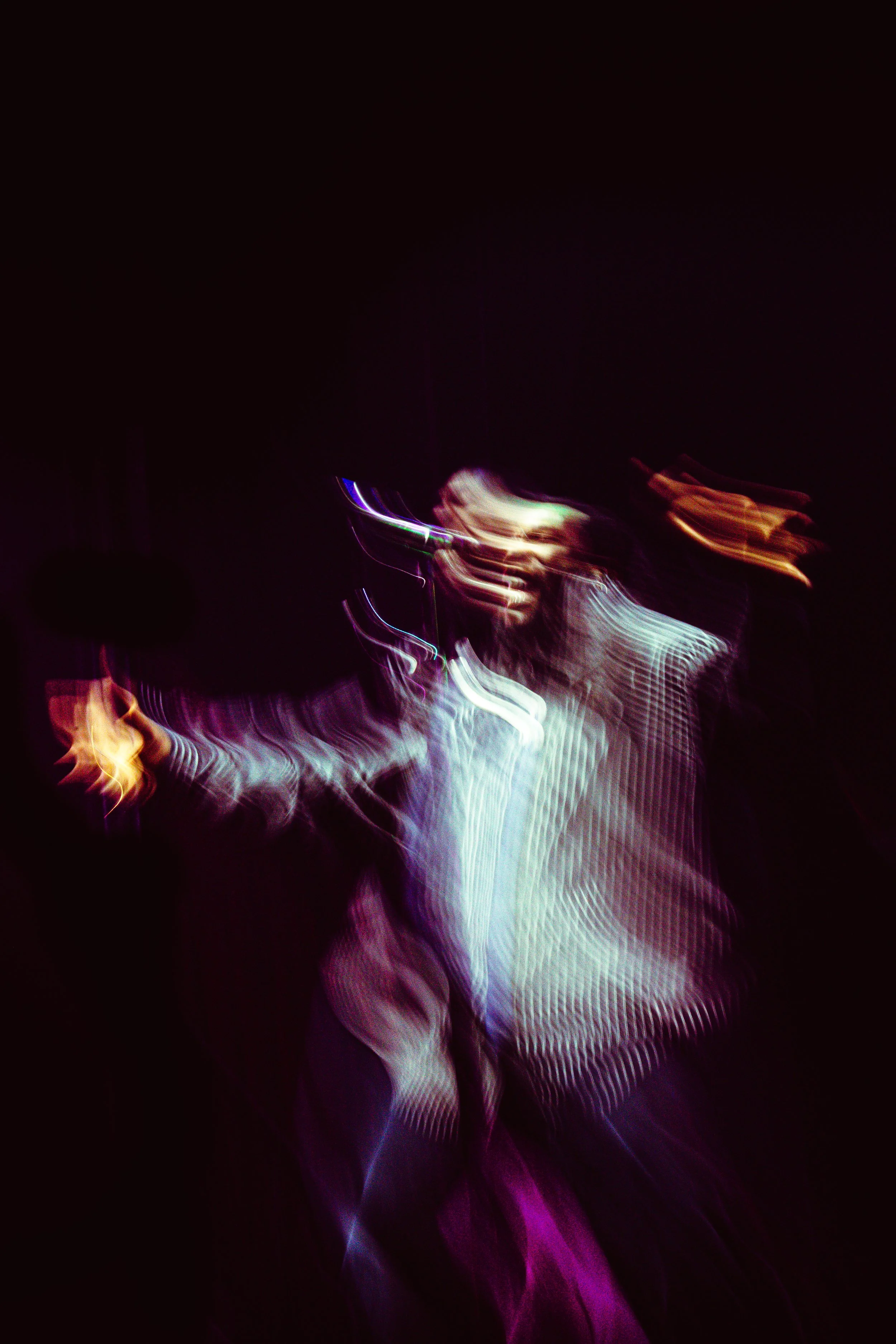 Imagem de cenas de luzes coloridas e figuras humanas desfocadas em movimento na escuridão.