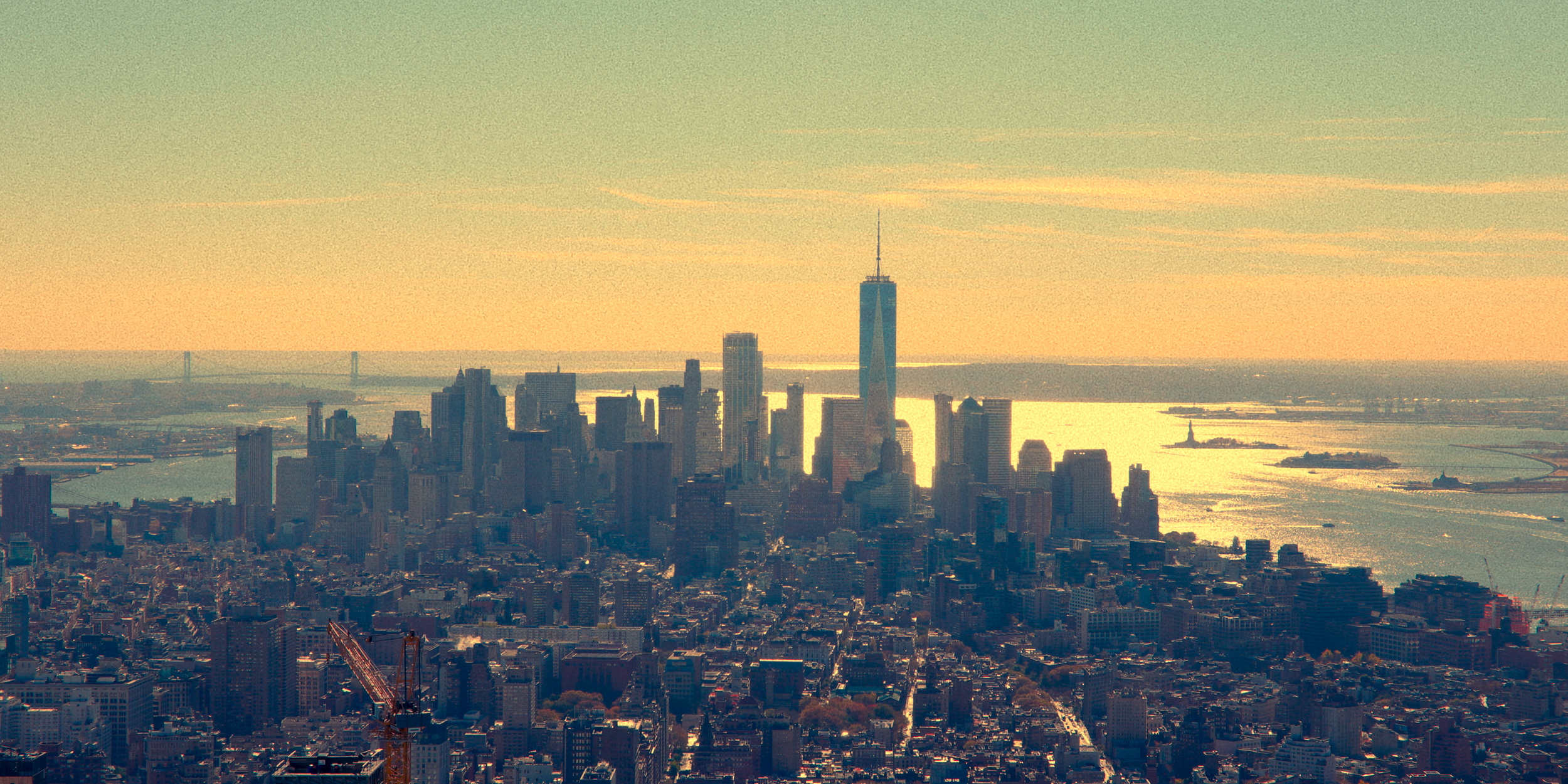 Vista do horizonte de Nova York ao pôr do sol, com arranha-céus, incluindo o One World Trade Center, e o rio Hudson ao fundo.