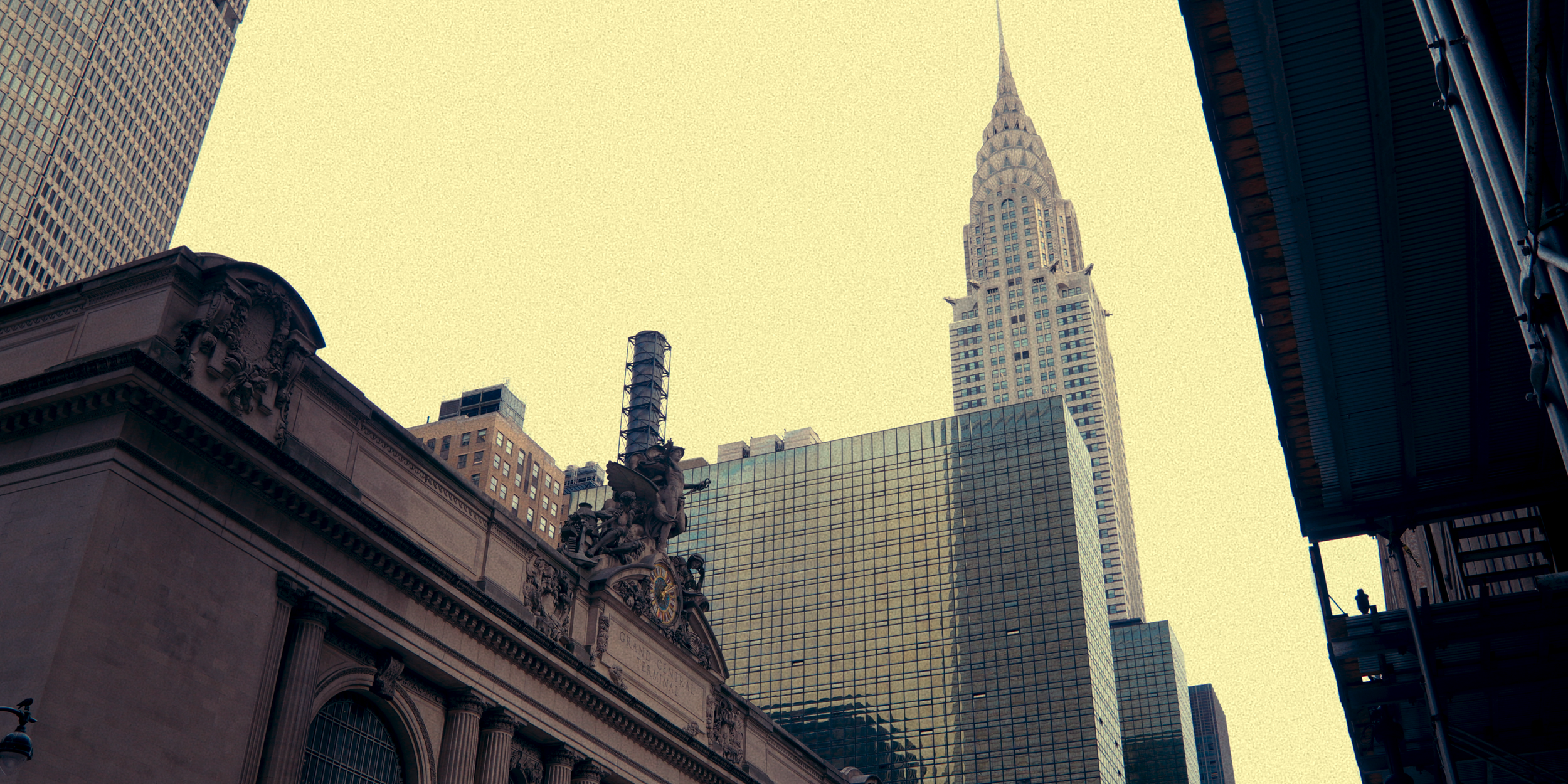 Arranha-céus em Nova York, com destaque para o Empire State Building ao fundo, visto da rua ao nível do chão.