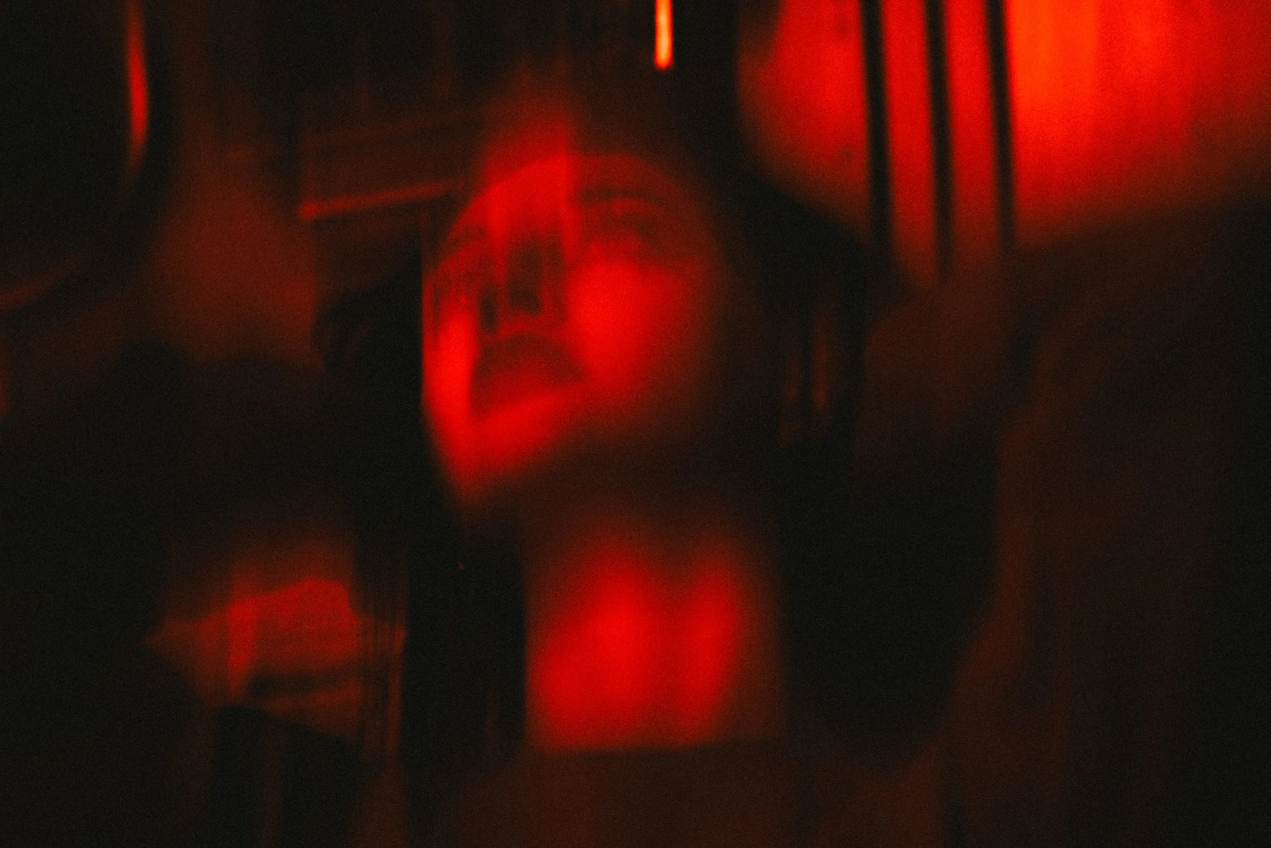 Abstract image of a person's face in red light with blurred and distorted features.