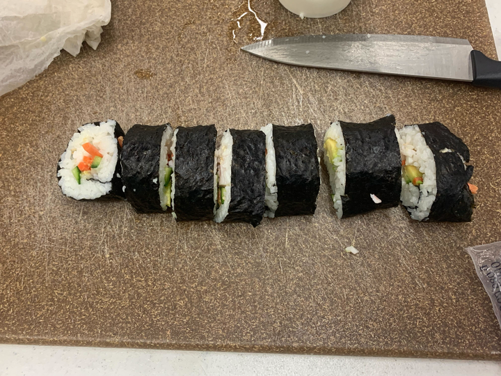 Sliced sushi roll on a cutting board with a knife