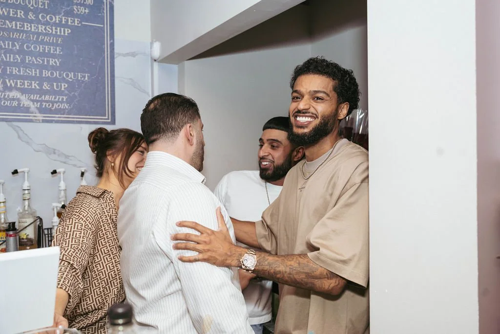 Four friends enjoying a friendly moment at a coffee shop, smiling and engaging in conversation.