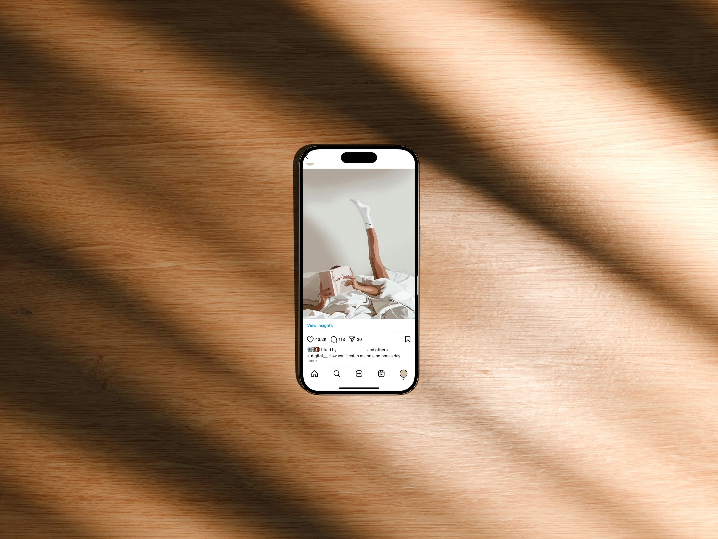 Smartphone on wooden surface displaying a social media post with an image of a person lying on a bed with their legs raised and crossed, wearing white socks, and holding a book.