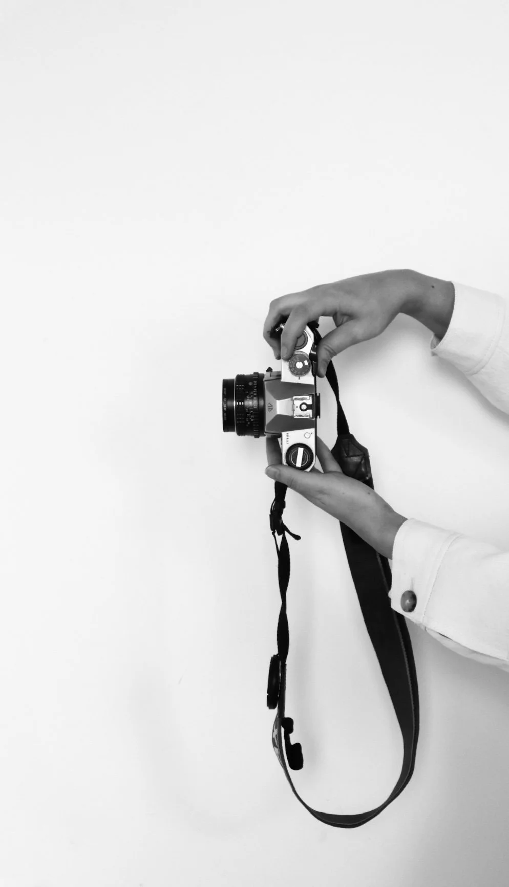 Person holding a vintage camera against a white background