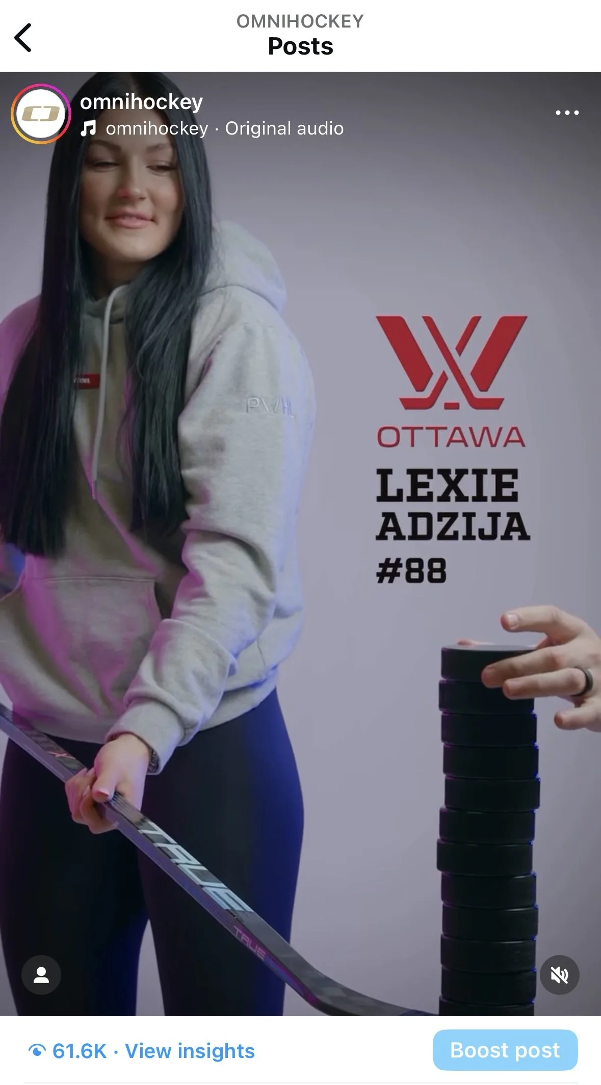 Person holding a hockey stick next to a stack of pucks, with Ottawa logo and text "Lexie Adzija #88" on the wall.