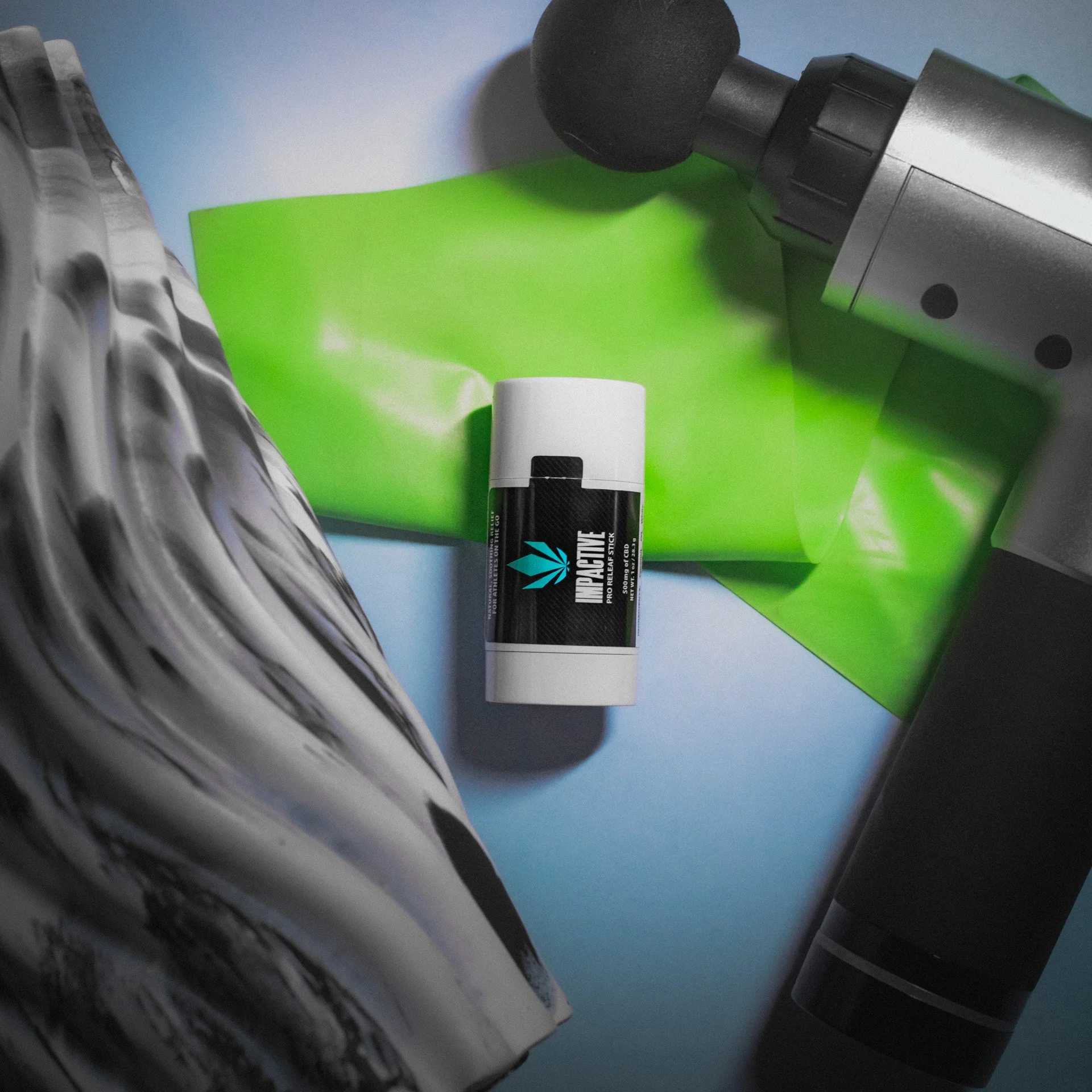 A massage gun, a fitness resistance band, and a black-and-white patterned foam roller are laid out with a stick of muscle relief balm on a green background.