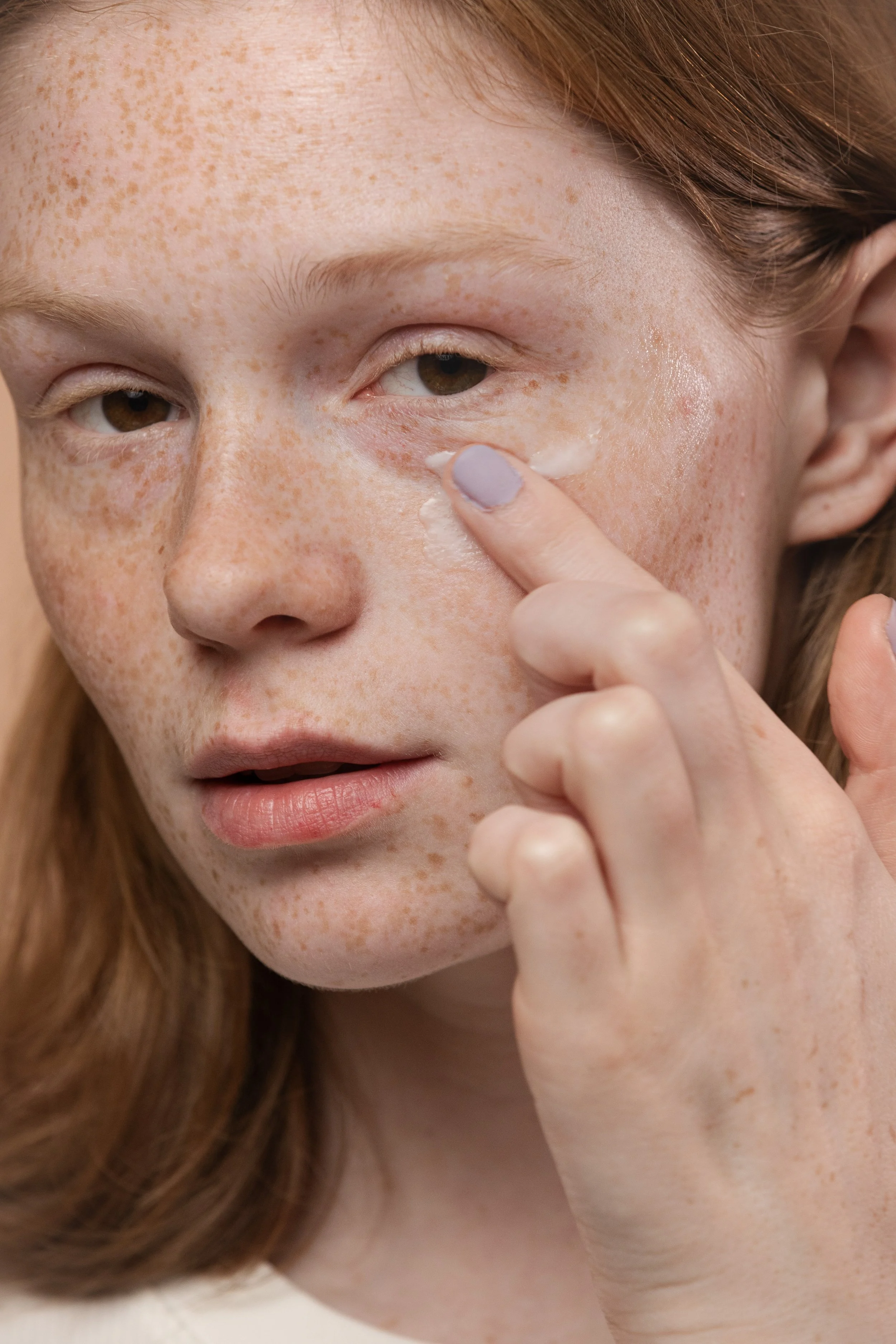 Close-up of a person applying cream under their eye