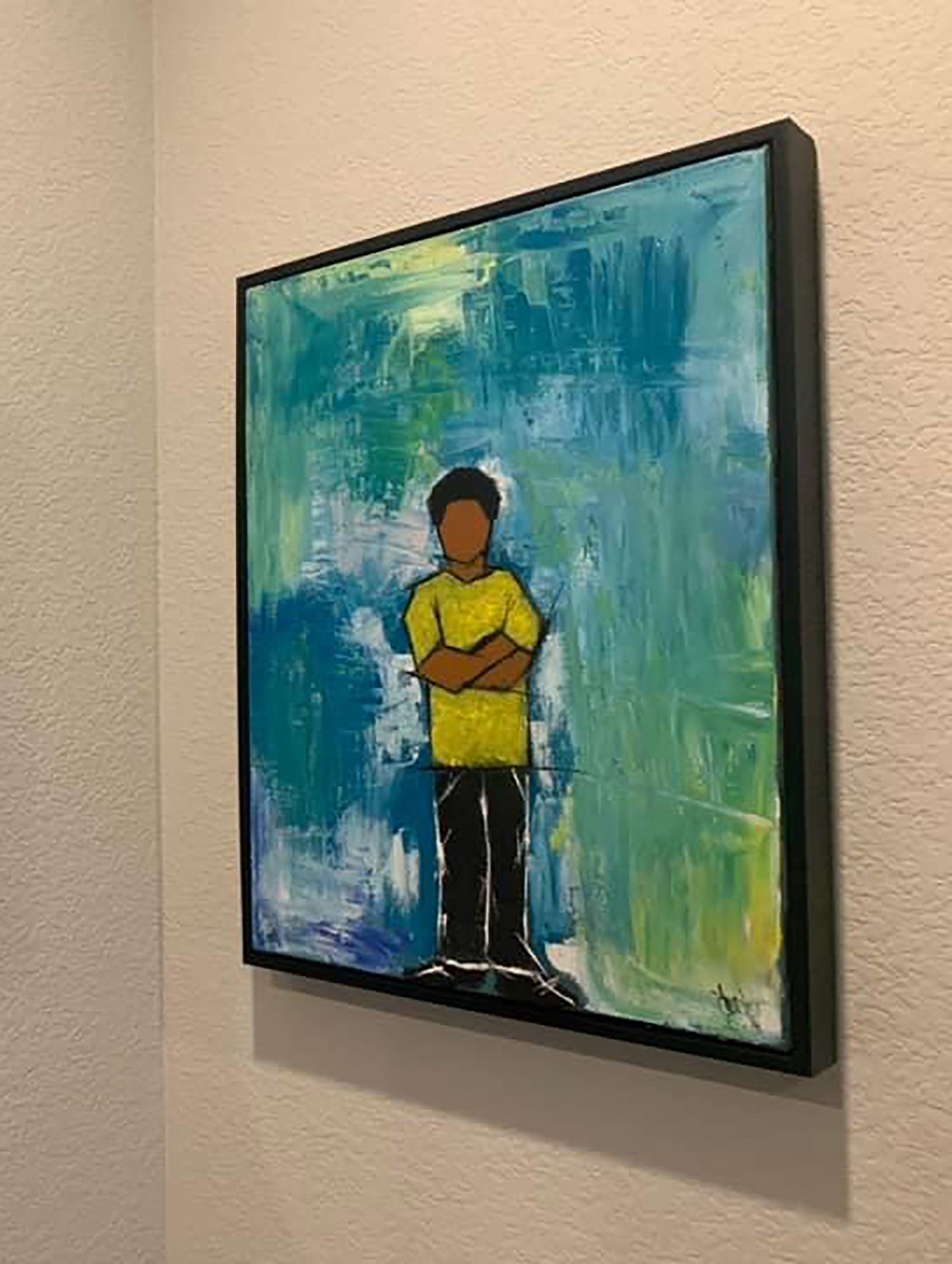 A framed painting on a wall depicting a simplified, abstract figure with a brown face and black hair, wearing a yellow shirt and black pants, set against a blue and green textured background.