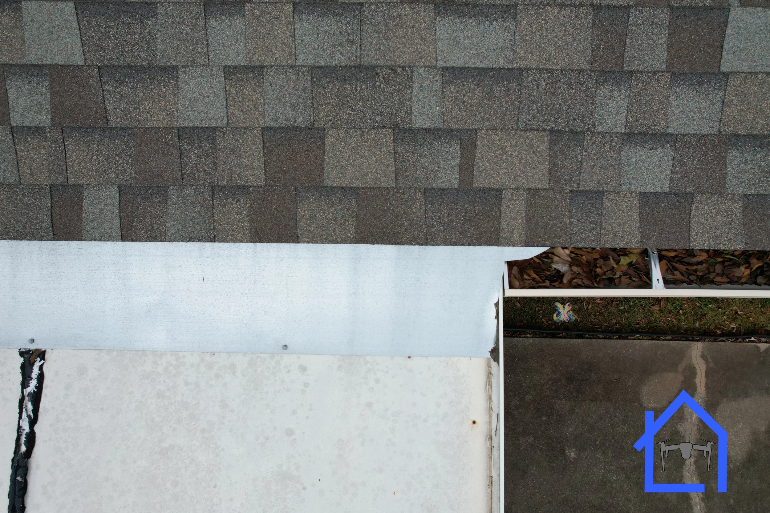 Aerial close-up view of where a flat patio roof meets the brown shingled roof of a residential home. 