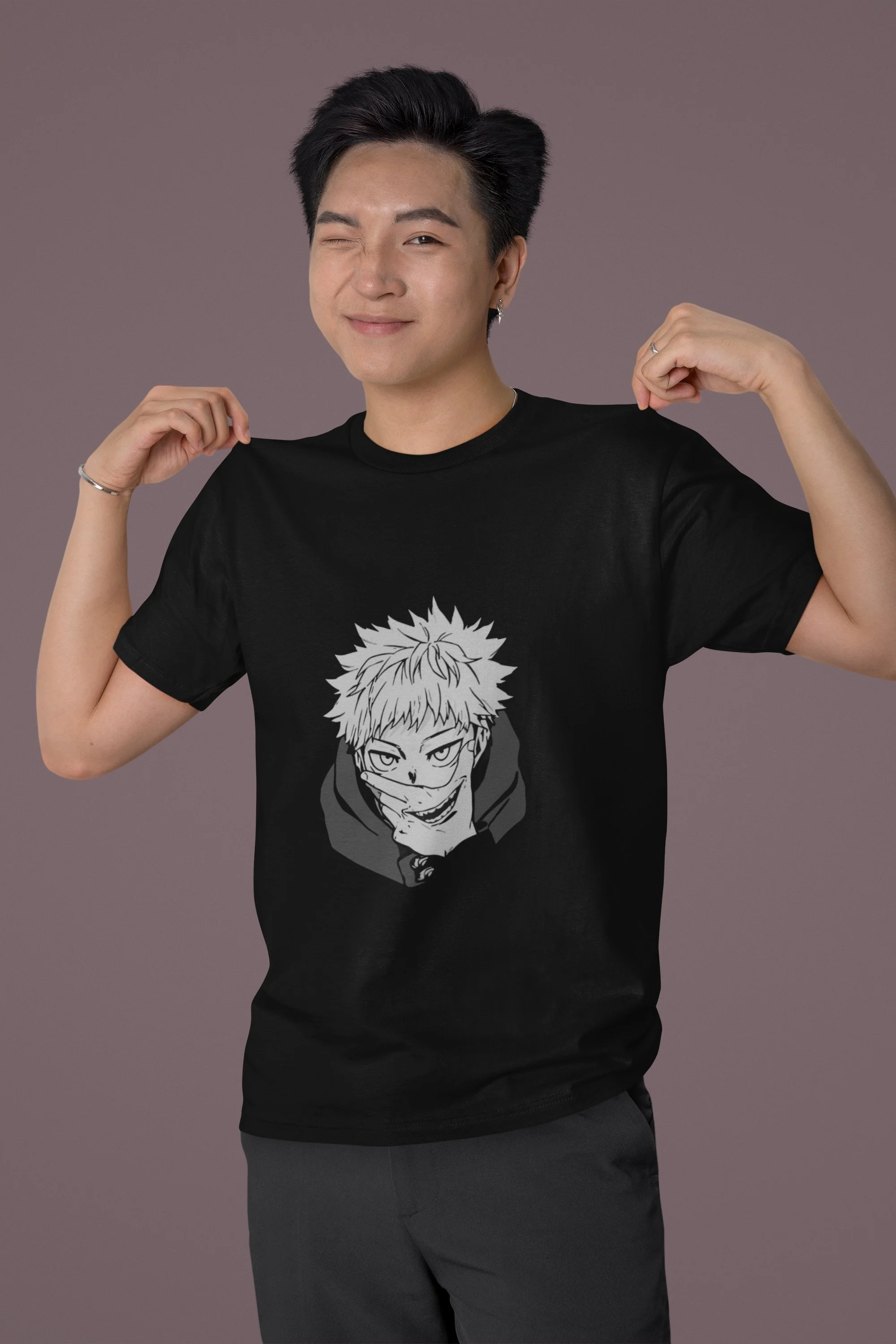 A person with short black hair wearing a black t-shirt with an anime character graphic, standing against a plain purple background, smiling and flexing their arms.