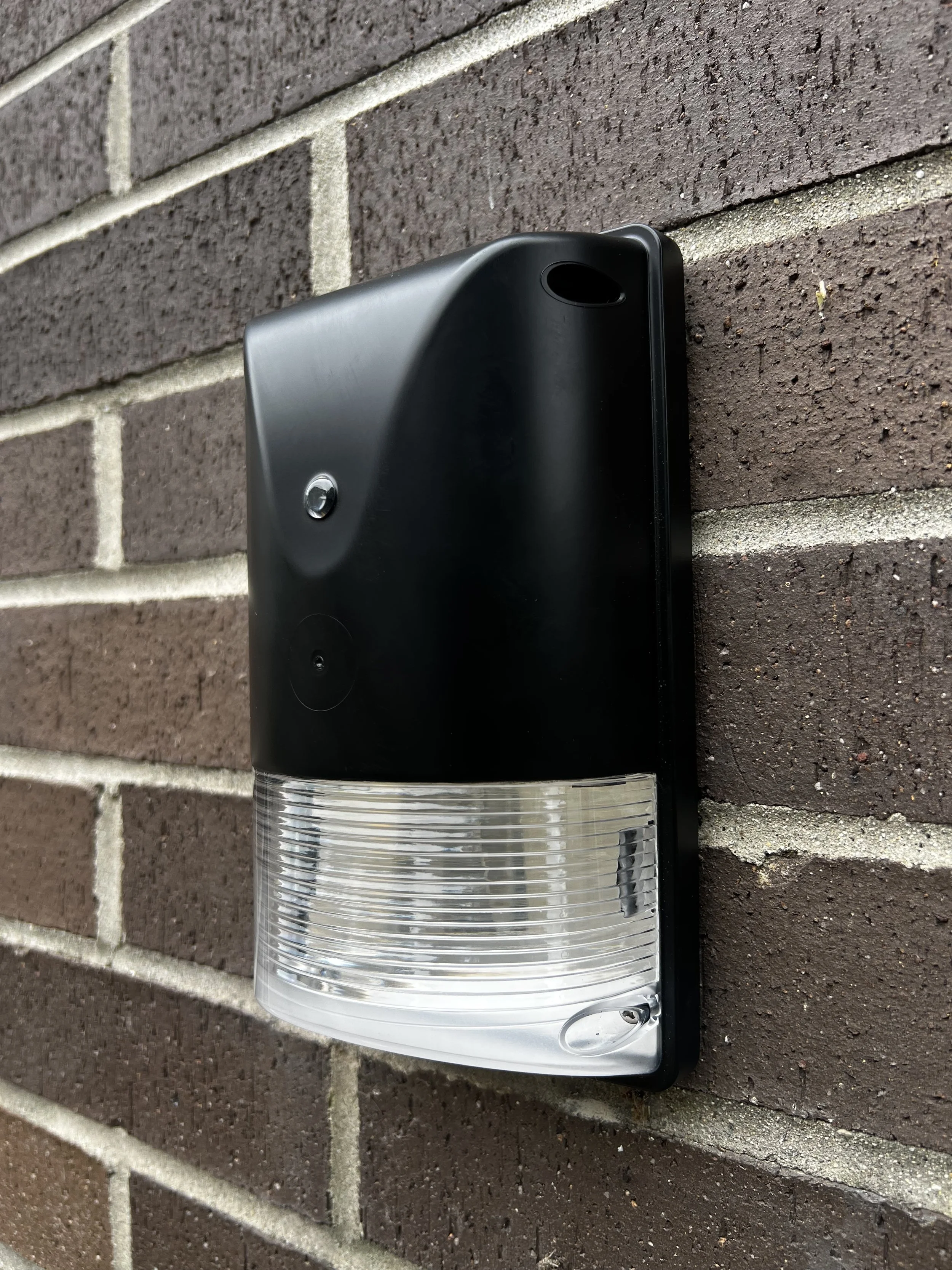 A black outdoor light fixture mounted on a brick wall.