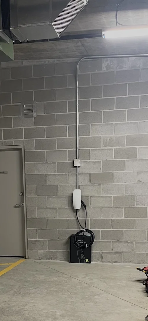 A white telephone mounted on a gray cinder block wall in a utility room.