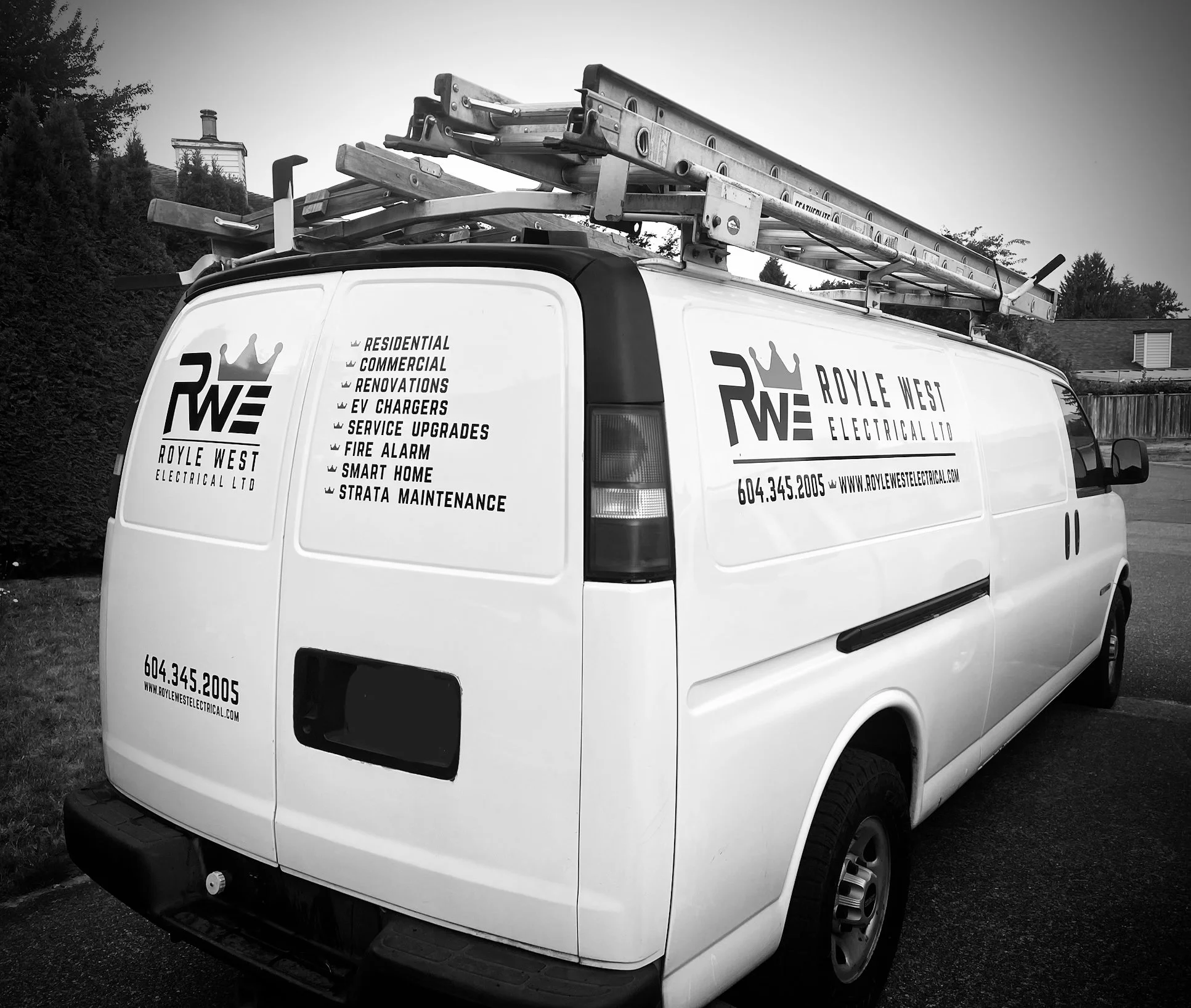 A white service van with company branding for Royle West Electrical Ltd. The van has a roof rack with ladders and equipment. The company logo and contact information are displayed on the side, along with a list of services including residential, commercial, and electrical upgrades.