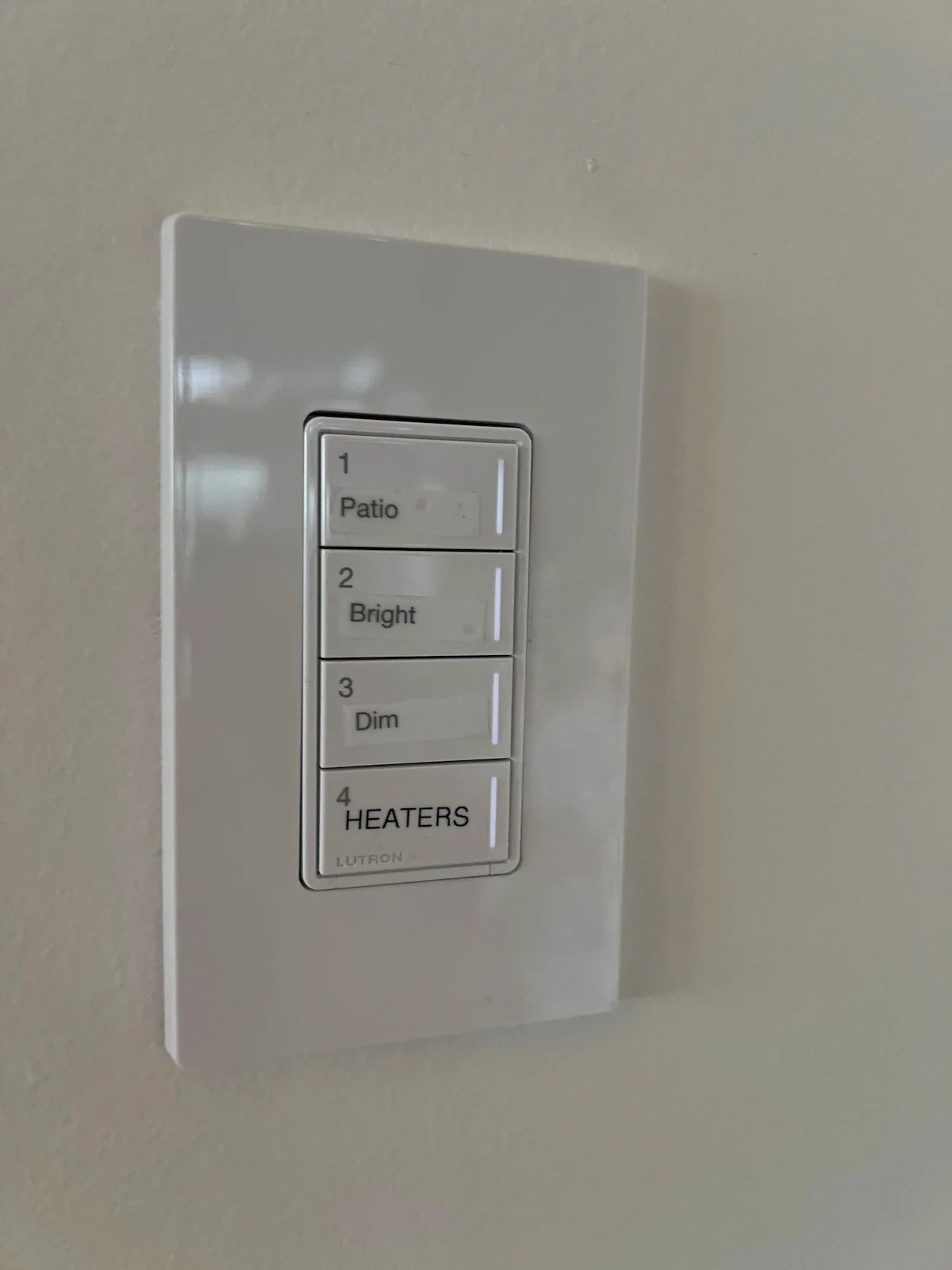 A white wall-mounted light switch panel with four labeled buttons: 1 Patios, 2 Bright, 3 Dim, 4 Heaters.