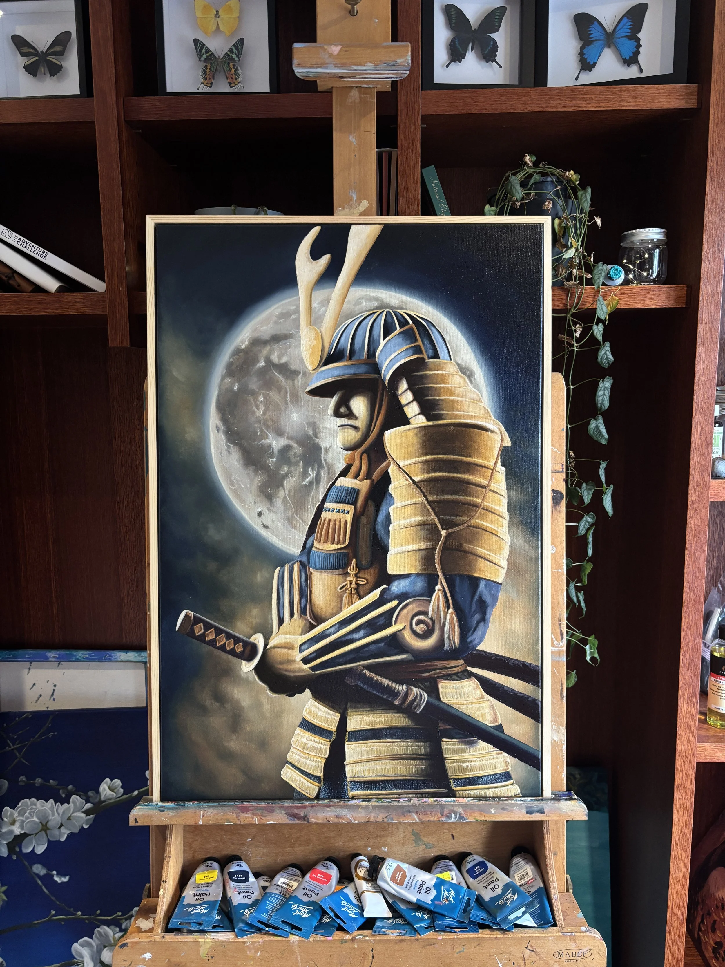 Painting of a samurai warrior in armor holding a sword with a full moon in the background.