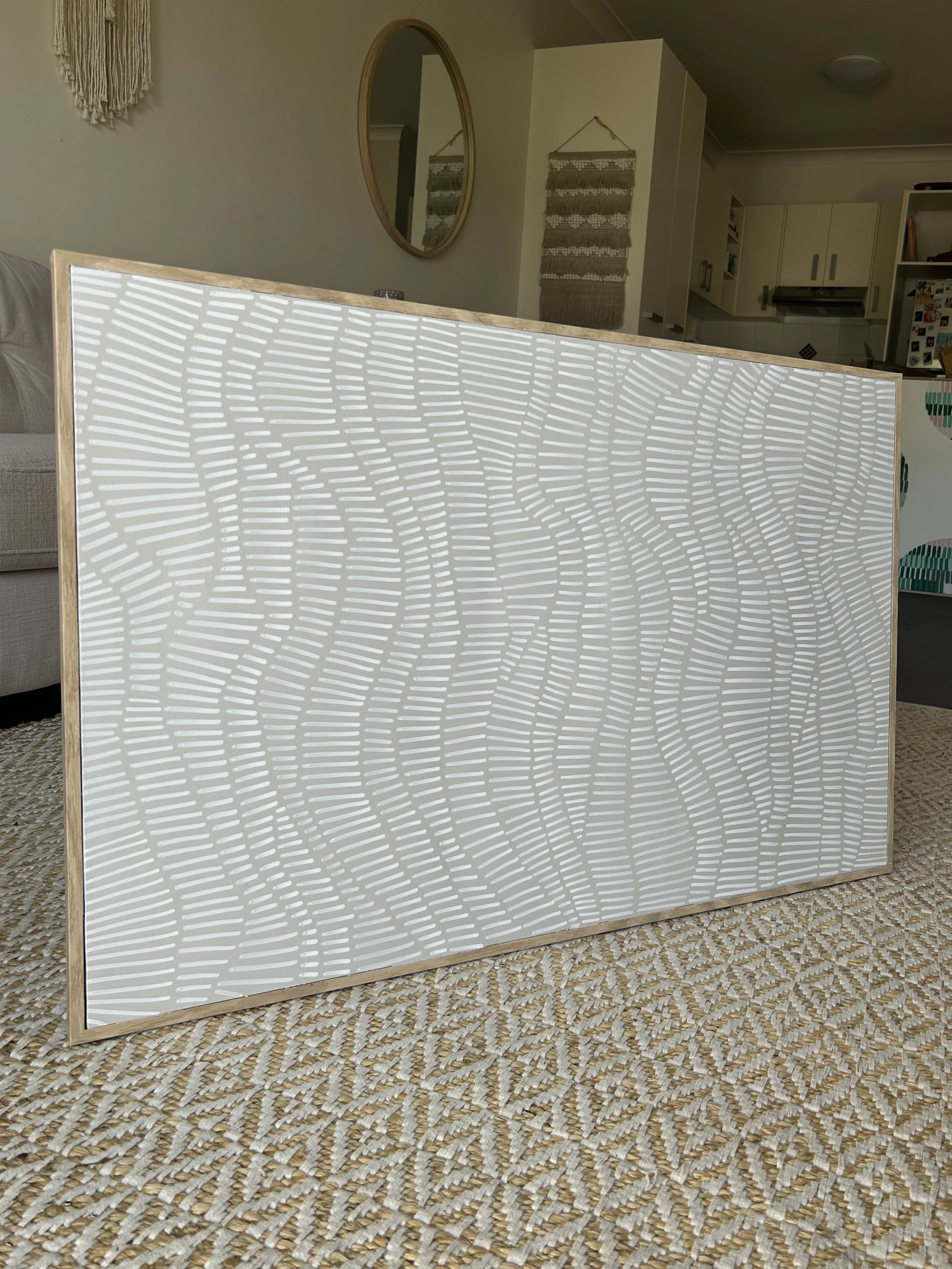 A decorative panel with a white wavy line pattern leaning against a wall in a living room.