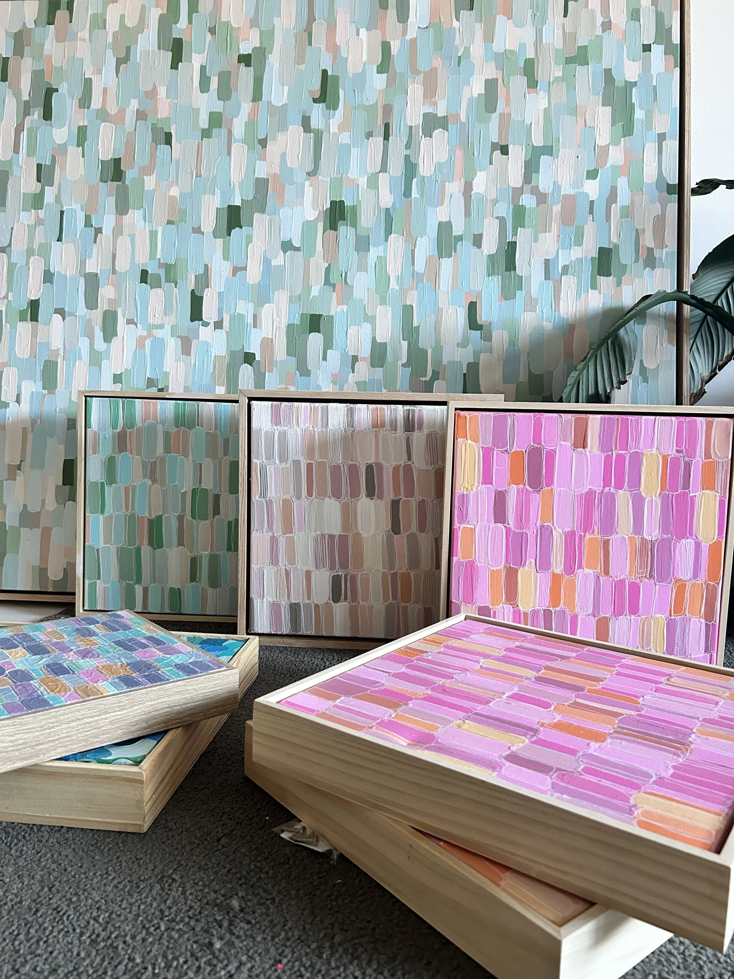 Collection of colorful abstract art paintings with brushstroke patterns in pink, purple, beige, green, blue, and gray, displayed against a matching patterned background.