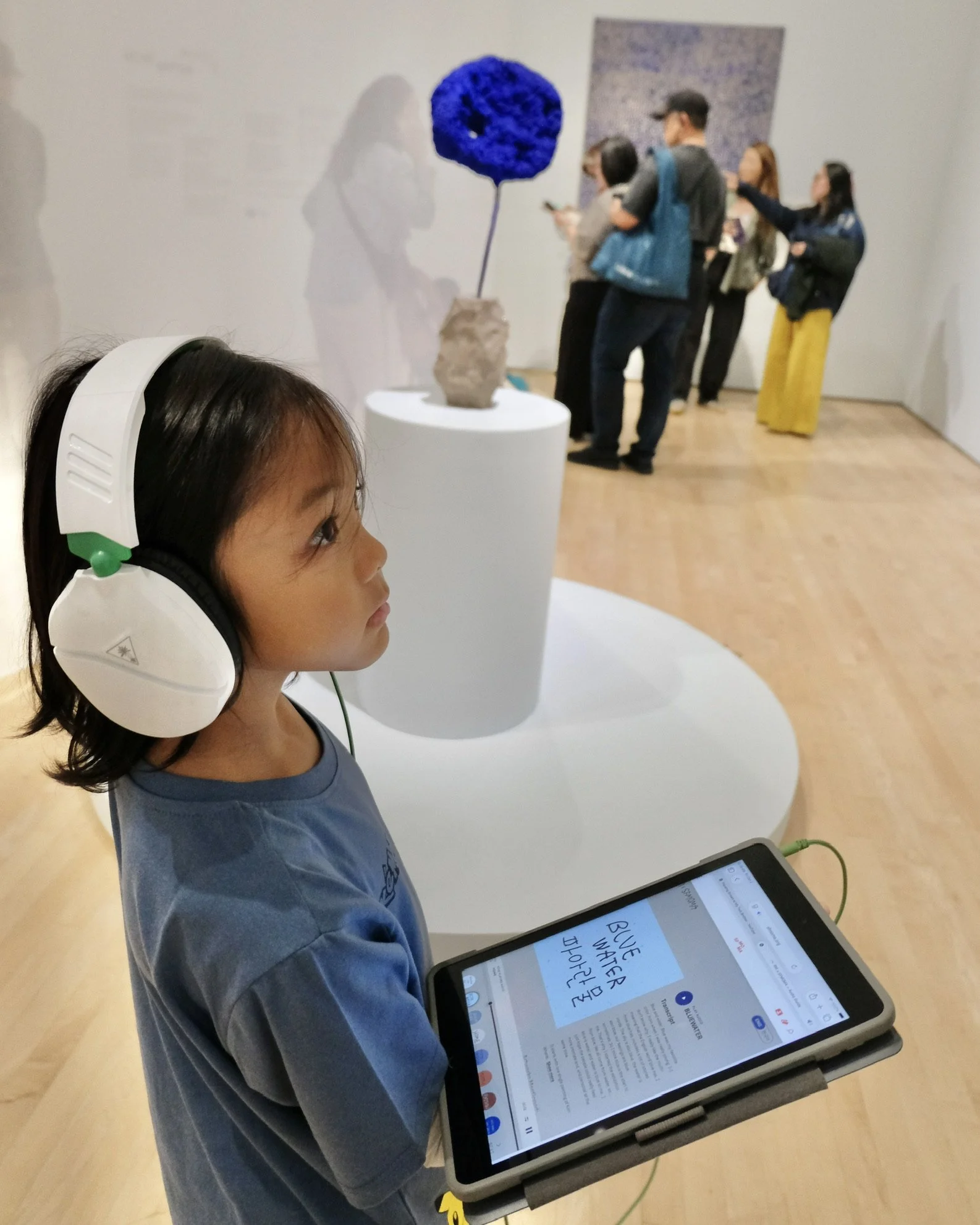 A young visitor listens to RM's audio guide beside Yves Klein's cobalt-blue sponge sculpture in the Blue Water gallery at SFMOMA.