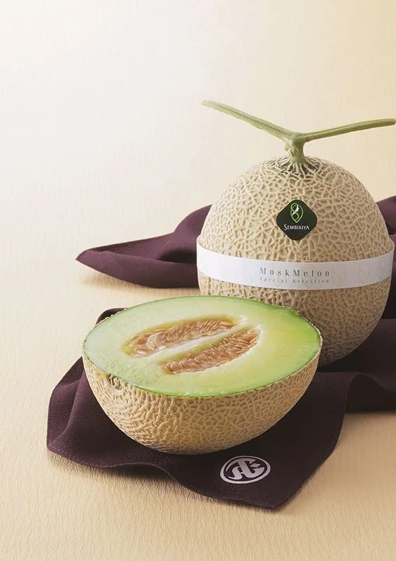 Premium Japanese muskmelon gift, shown whole and halved, traditionally given as a formal fruit gift in Japan.