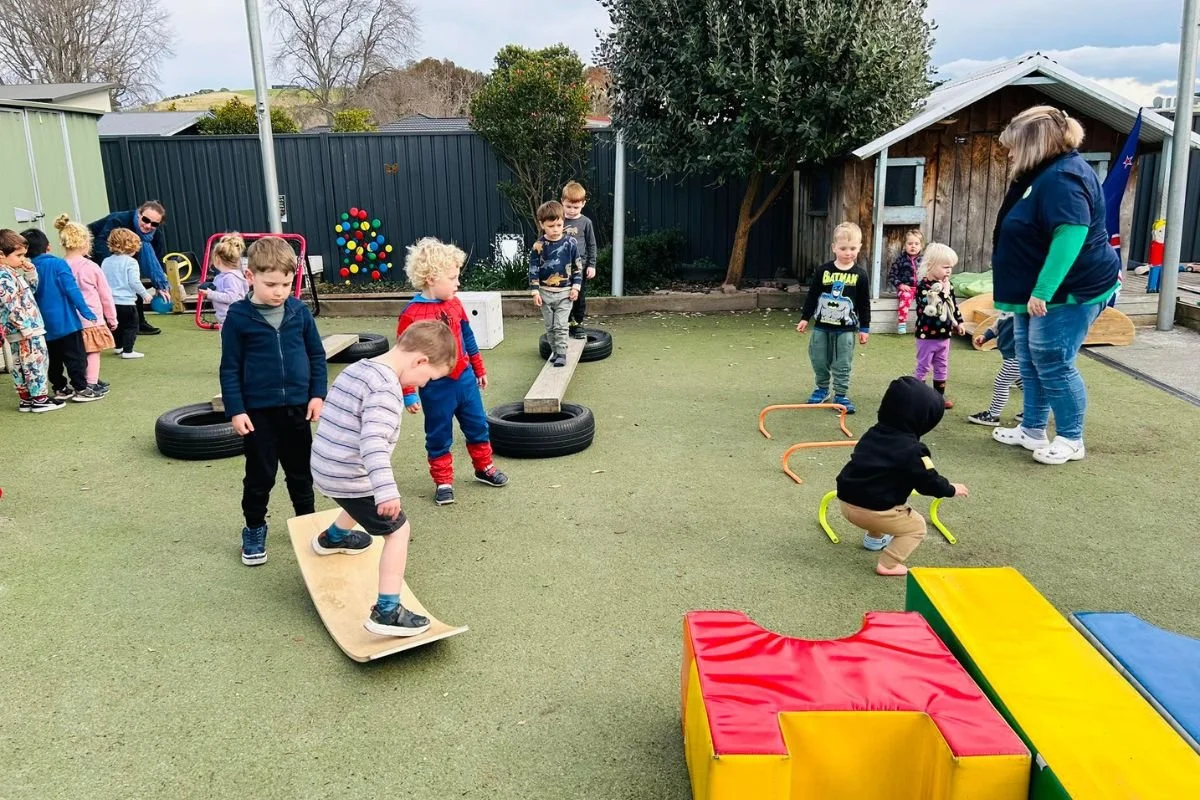Preschoolers navigating an outdoor obstacle course at Happy Days Taradale, building confidence and gross motor skills through physical play.