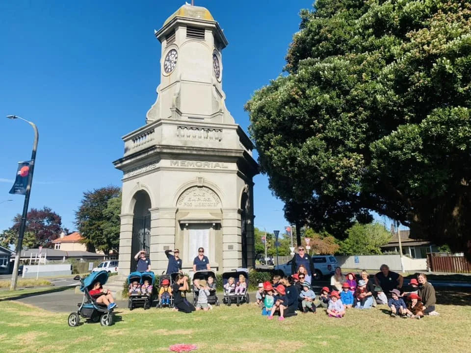 Teachers and tamariki from Happy Days Taradale visiting the local Memorial Clock Tower for an Anzac Day outing, connecting to place and community.