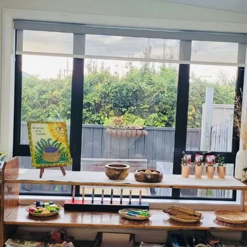 A peaceful learning space at Happy Days Childcare featuring wooden shelves, nature-based learning materials, and a view of the garden through large windows.